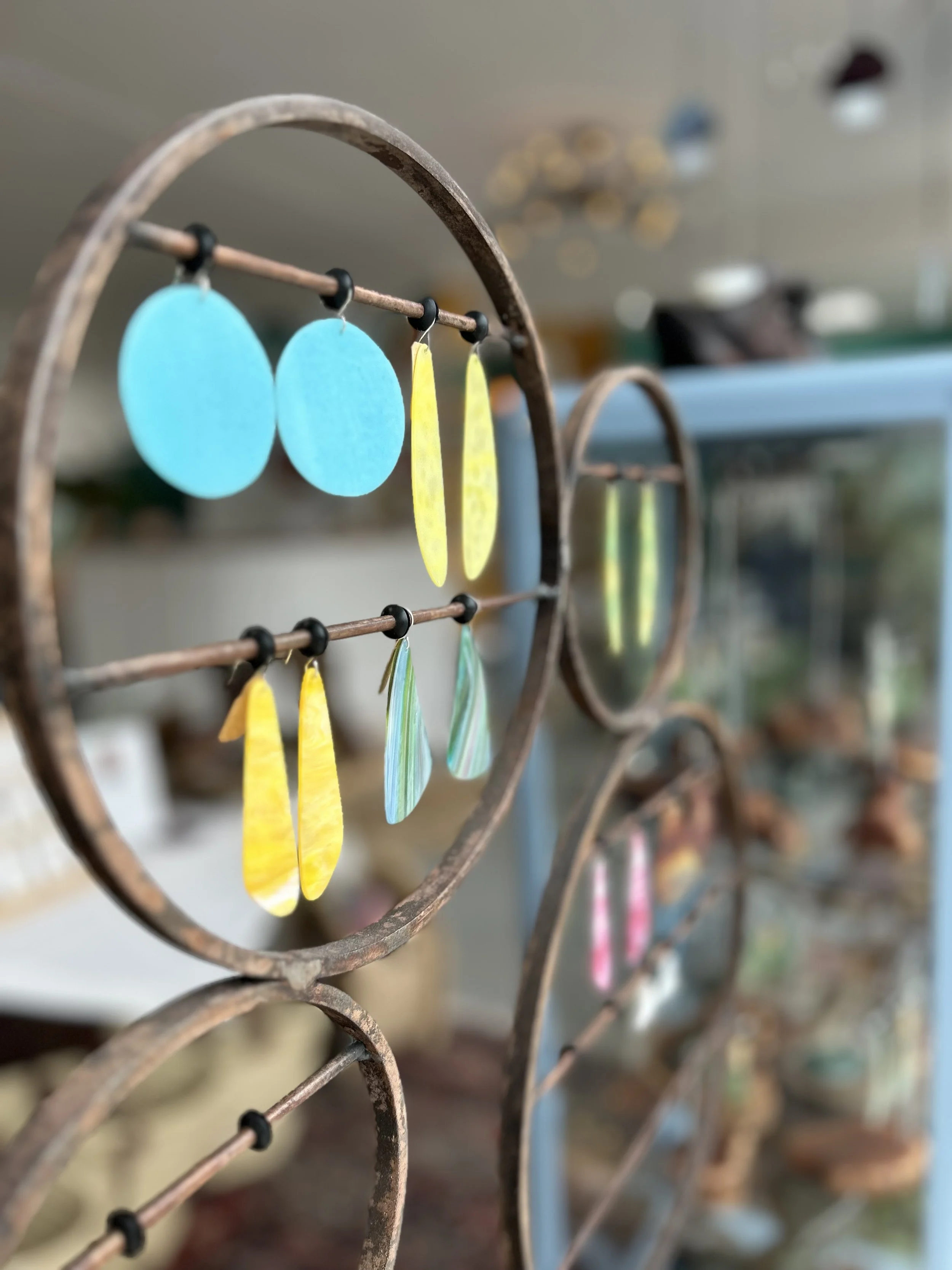 Colorful earrings displayed on a rustic metal stand in a boutique shop.