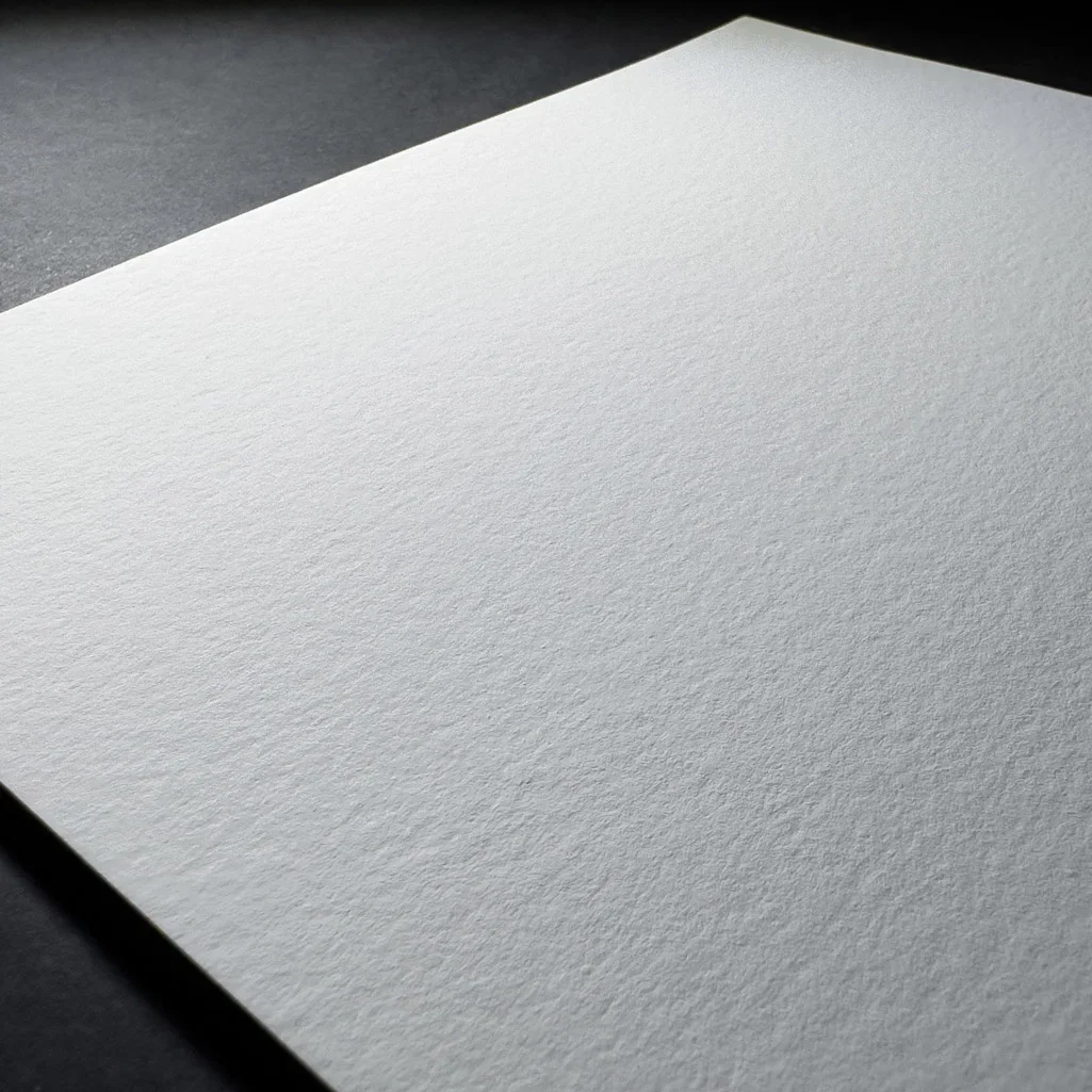 Et hvitt, tomt ark liggende på en svart overflate.