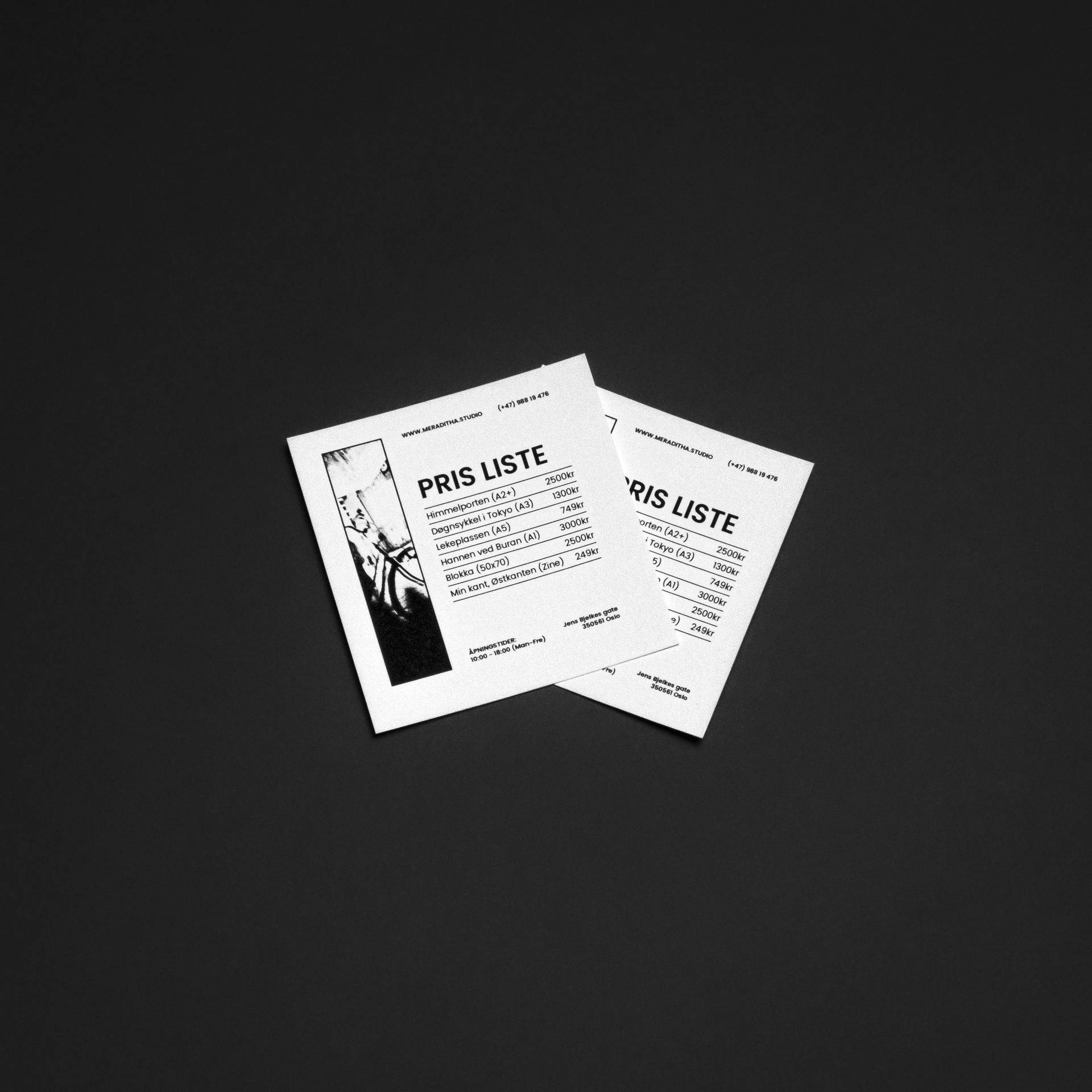 To svart-hvite menyer med prisliste ligger på en sort overflate.