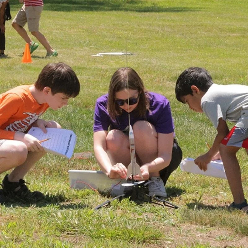 Kids participating in a summer STEAM camp, conducting an outdoor science and engineering experiment