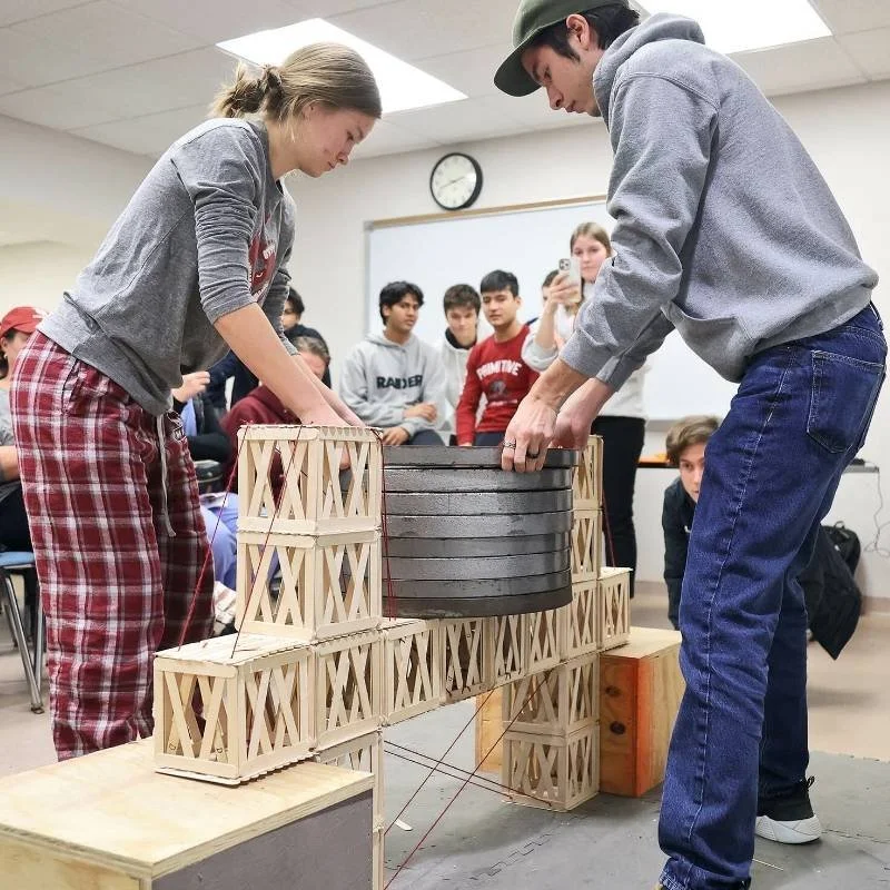 Students participating in a hands-on math and engineering program, testing a bridge design and learning structural problem-solving skills