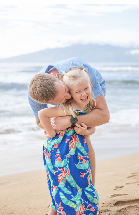 Father hugging his young daughter during a family photography session on a Maui beach