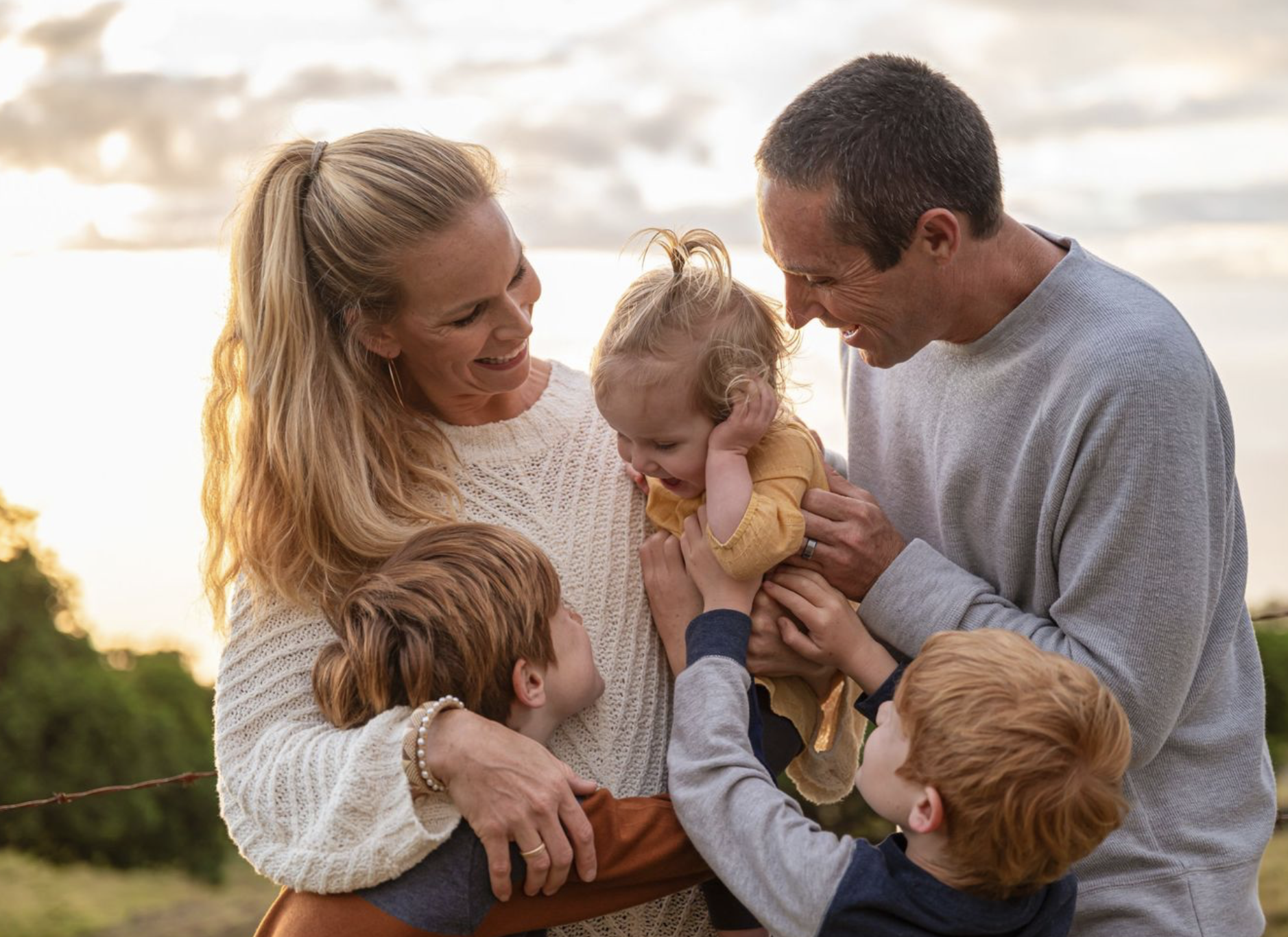 Parents smiling with their three young children during a Maui family photography session