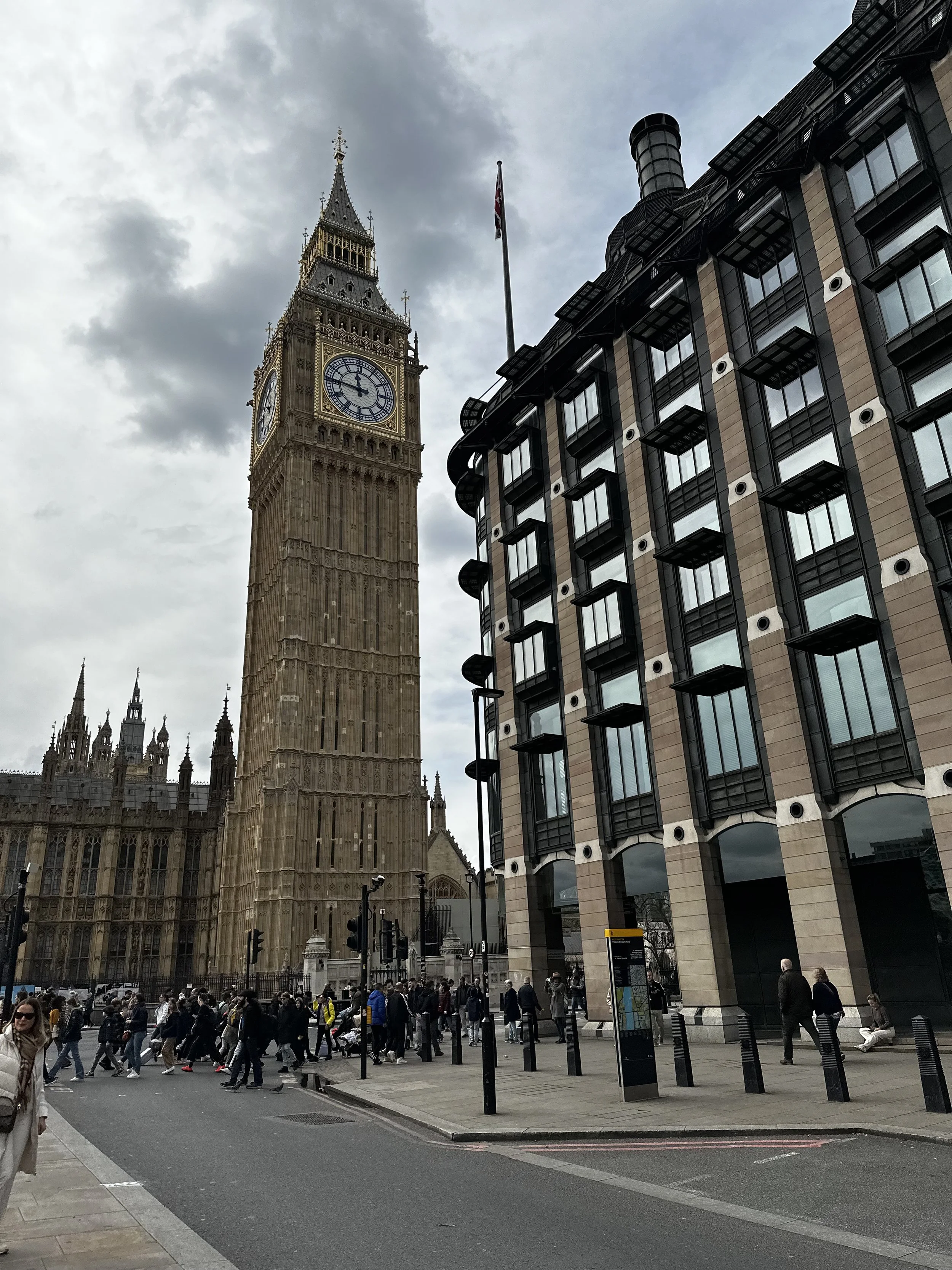Big Ben and the Palace of Westminster in London with pedestrians walking below.
