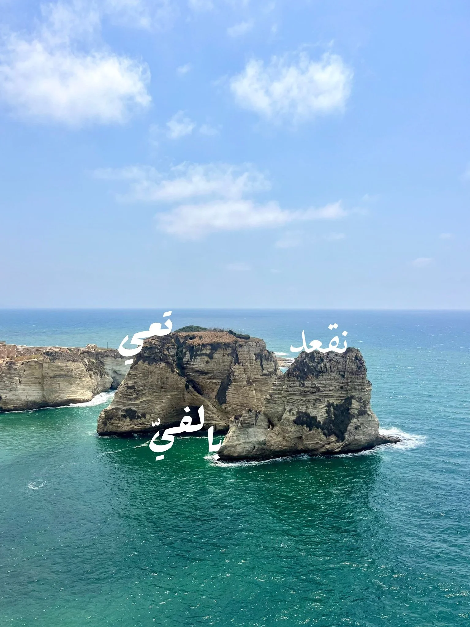 Sea stacks at the coast with blue sky and clouds, with Arabic text overlay.