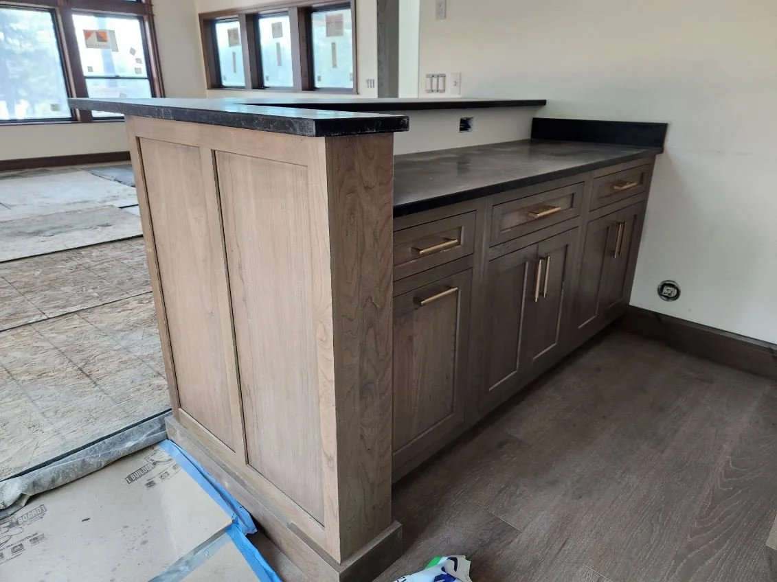 Kitchen counter with dark countertop, wooden cabinets with gold handles, and a half wall or divider.