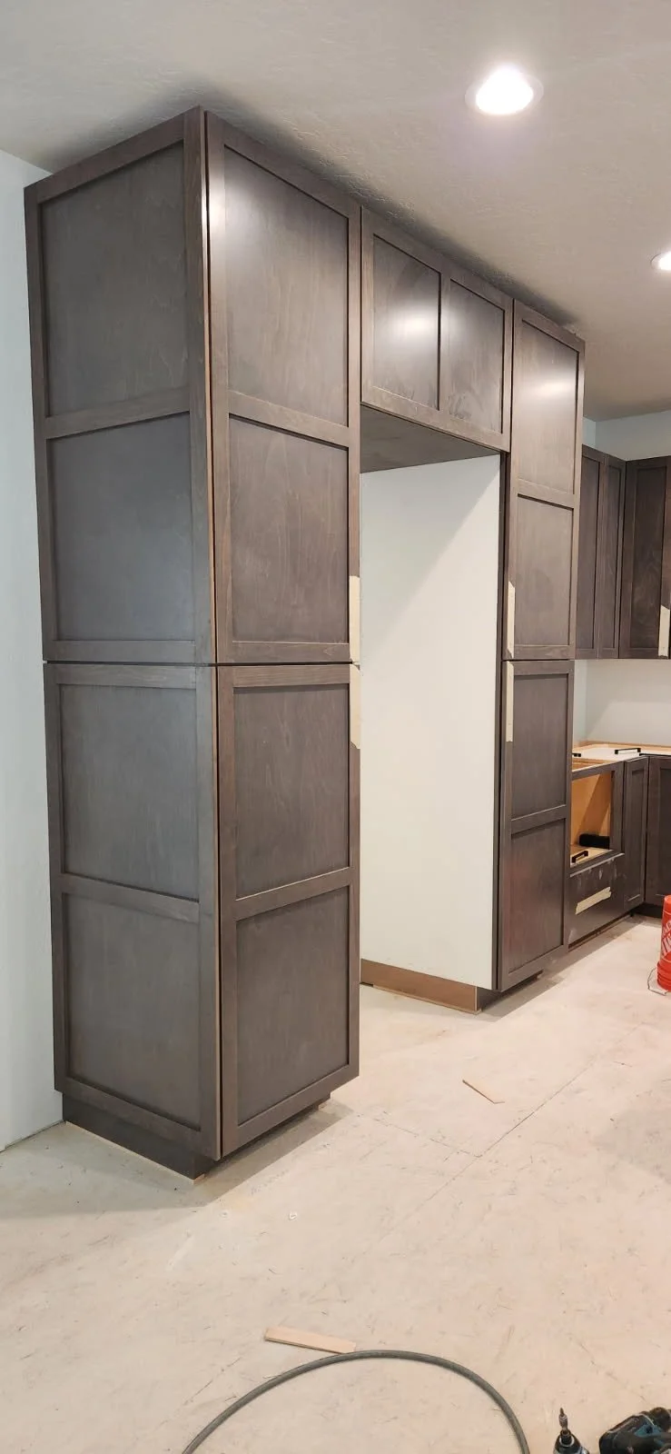 Dark wooden kitchen cabinets being installed in a home under construction or renovation.