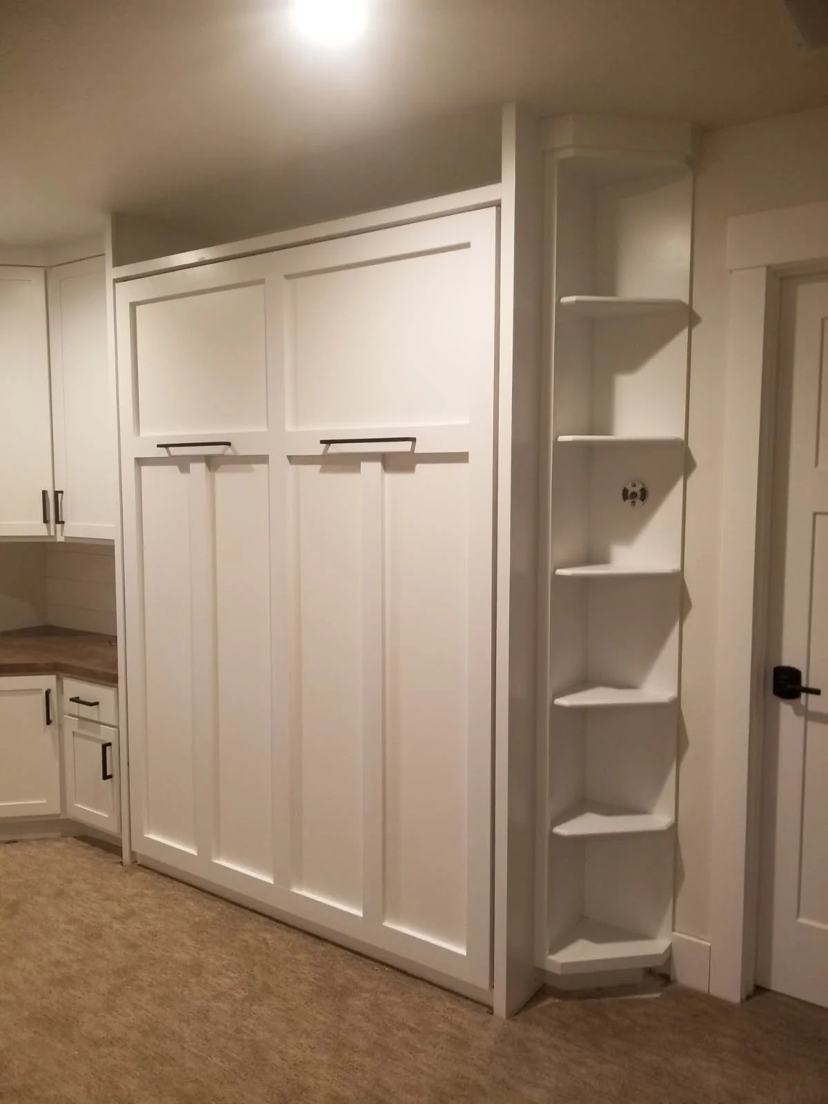 Empty white built-in closet with hanging space and shelves in a room with beige carpet.