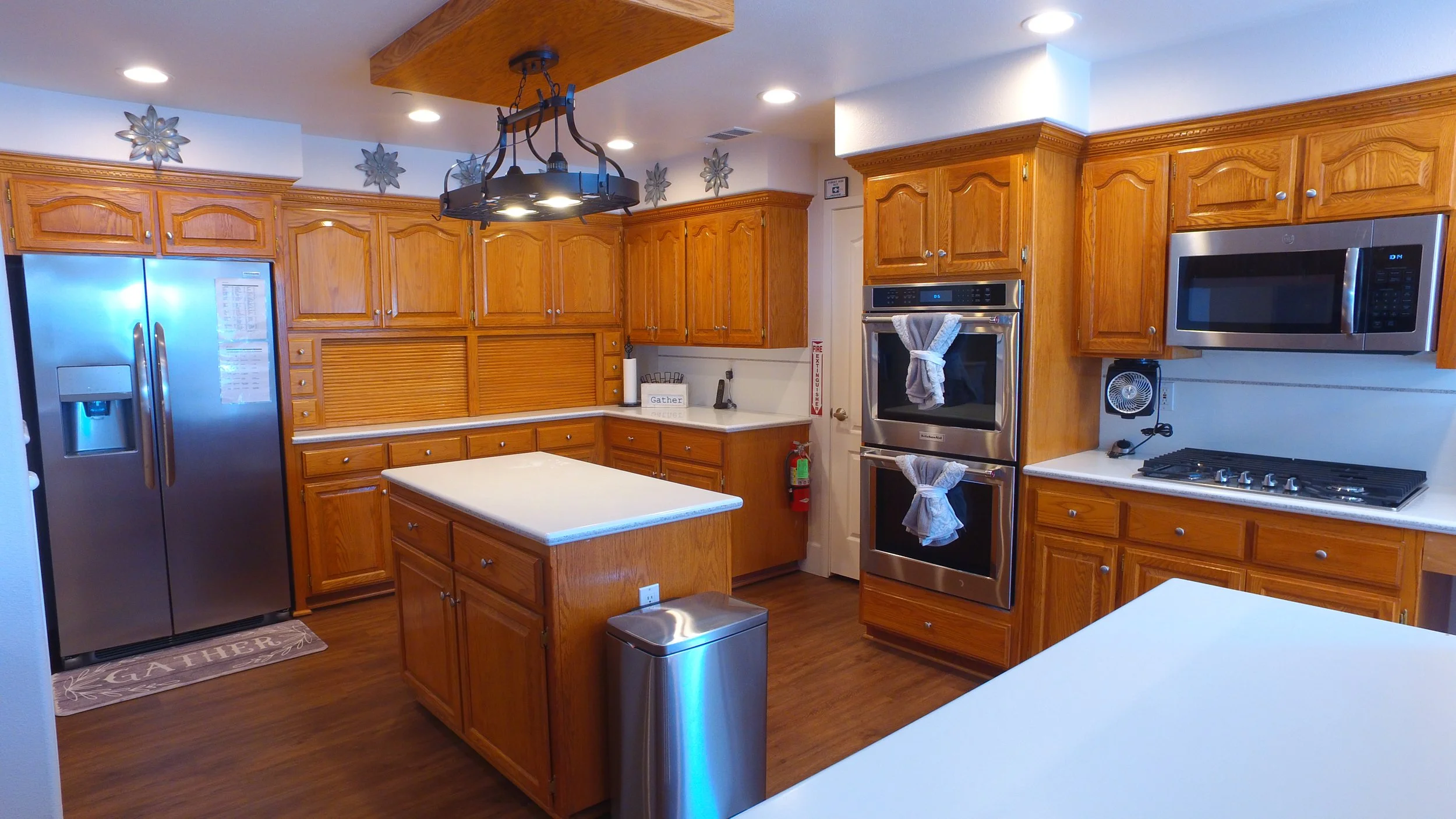 Kitchen with wooden cabinets, stainless steel appliances, and a kitchen island with a white countertop.