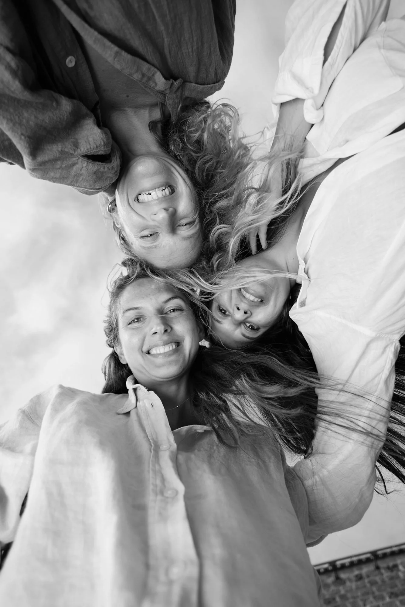 Black and white photo of four women smiling and looking down at the camera.