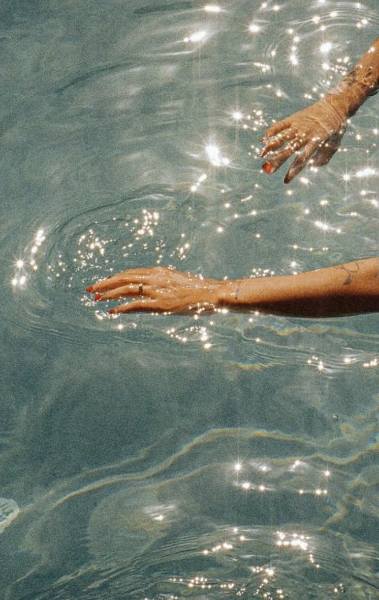Hand touching sparkling sea water, shot on vintage film grain style. Nostalgic summer vibes in Italy.