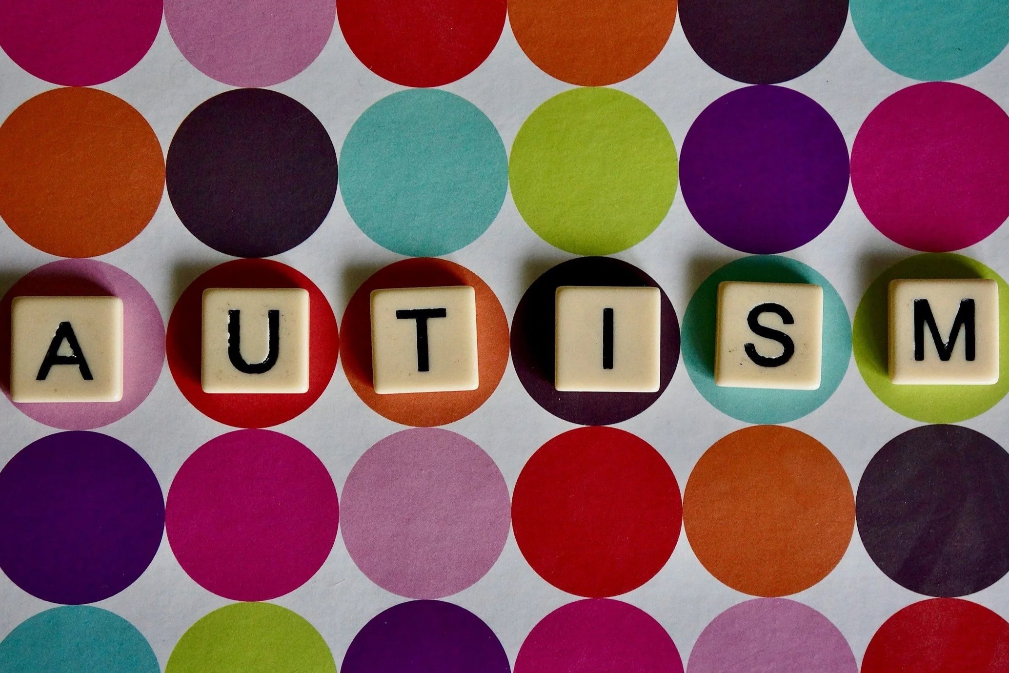 Farvet baggrund med små farvede cirkler, ord dannet af terninger med bogstaverne A, U, T, I, S, M.