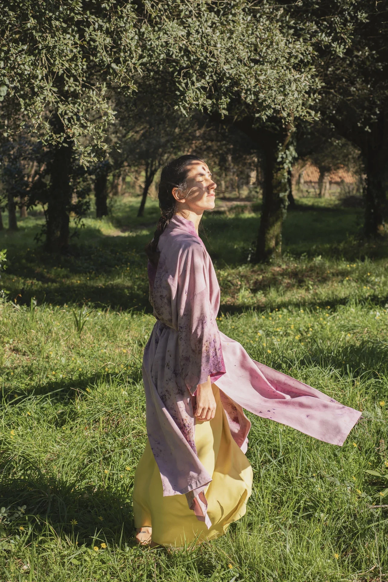 Mujer meditando al aire libre, vistiendo un kimono fluido color morado de fibra de loto con estampado botánico eco-print.