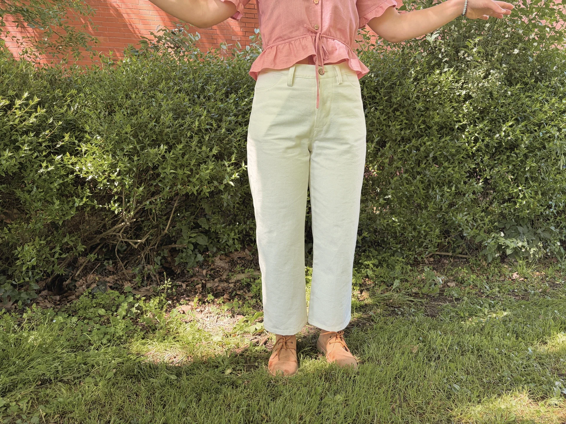 Mujer en la naturaleza vistiendo el Pantalón Luna de estilo denim. Pantalón de corte recto confeccionado en algodón orgánico natural con cierre de botones de coco. Moda consciente y sostenible.