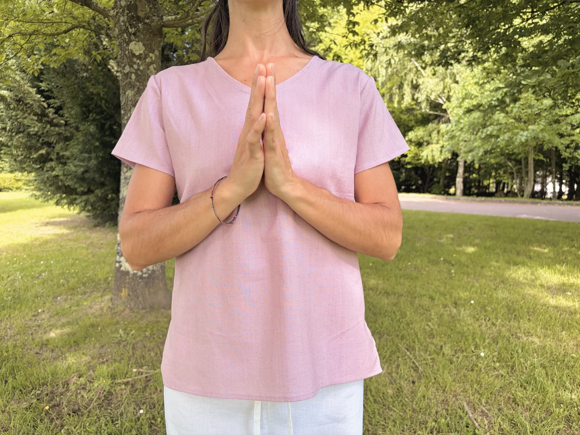 Mujer practicando yoga al aire libre vistiendo un top lila claro de manga corta en algodón orgánico teñido con tintes naturales libre de tóxicos