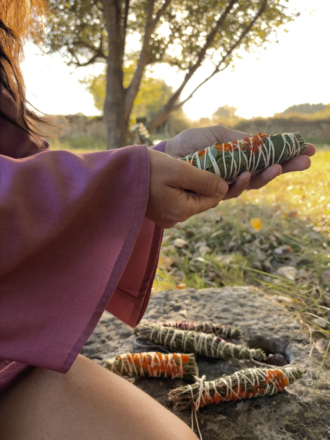 Mujer en la naturaleza luciendo la blusa mística Devi en color violeta, destacando las amplias mangas acampanadas y el tejido teñido con plantas medicinales