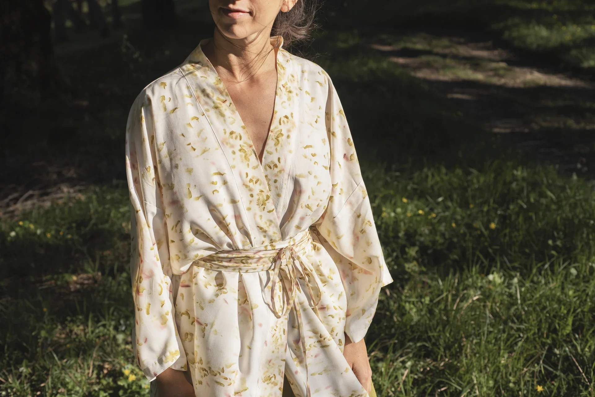 Mujer en la naturaleza vistiendo un kimono cruzado de fibra de loto con estampado botánico eco-print, medicina