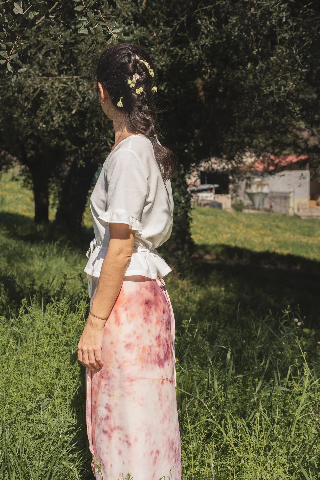 Blusa Aura de algodón orgánico en blanco, destacando sus botones de madera en forma de flor y el lazo ajustable en la cintura.