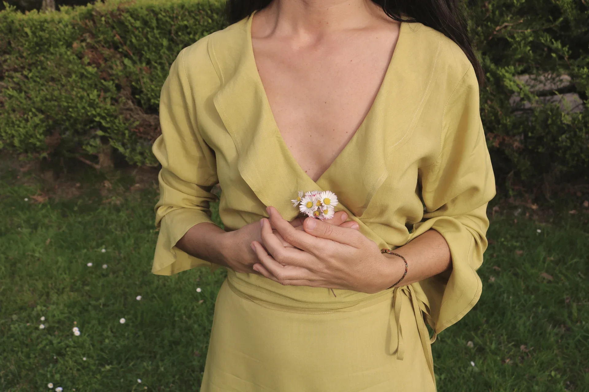 Mujer paseando por el campo vistiendo el vestido cruzado Agni en color marrón. Confeccionado en fibra de loto, alternativa vegana a la seda, y teñido con piel de granada y catechu