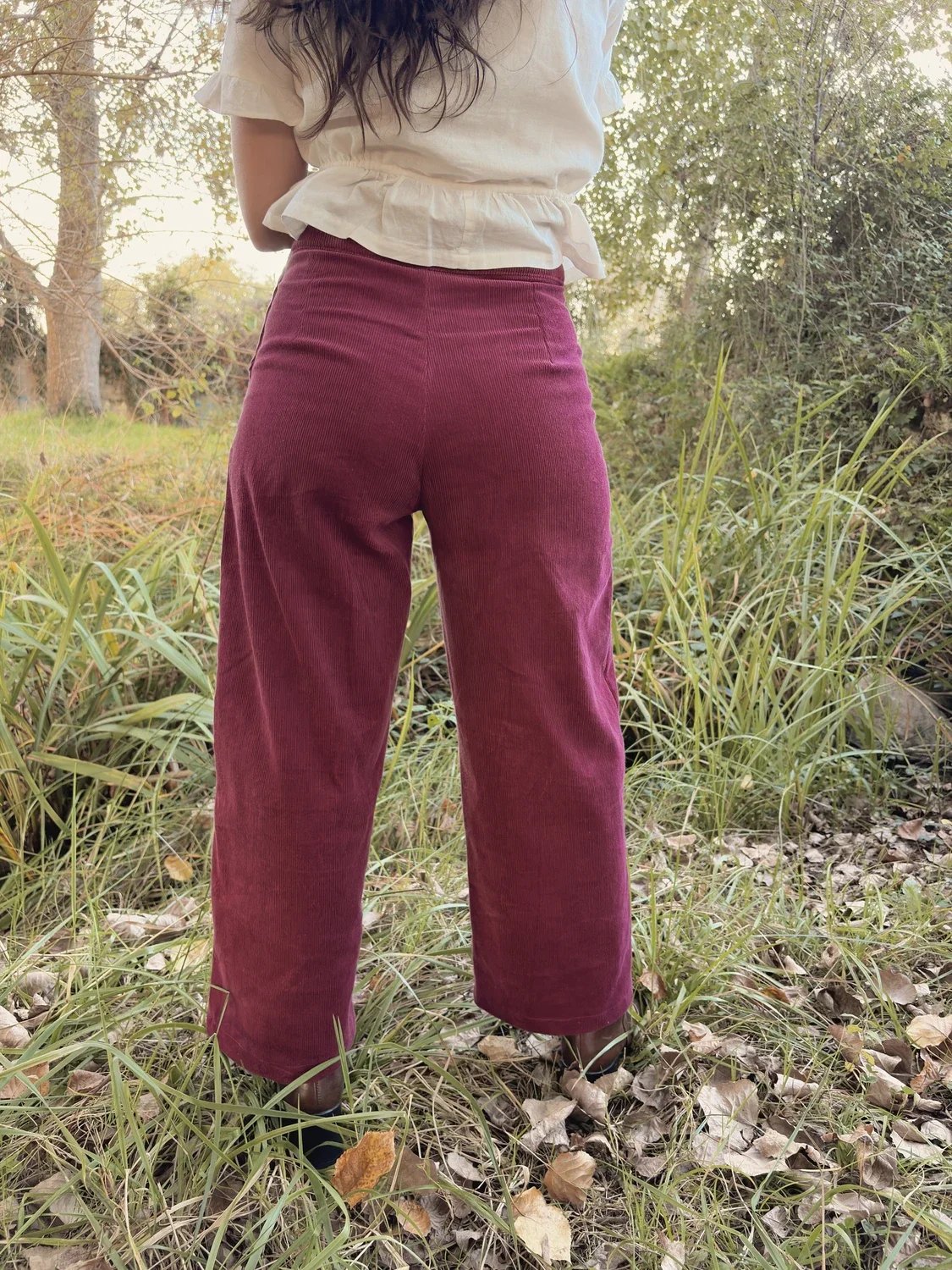 Mujer sonriente en el bosque luciendo el pantalón Indira de pana.