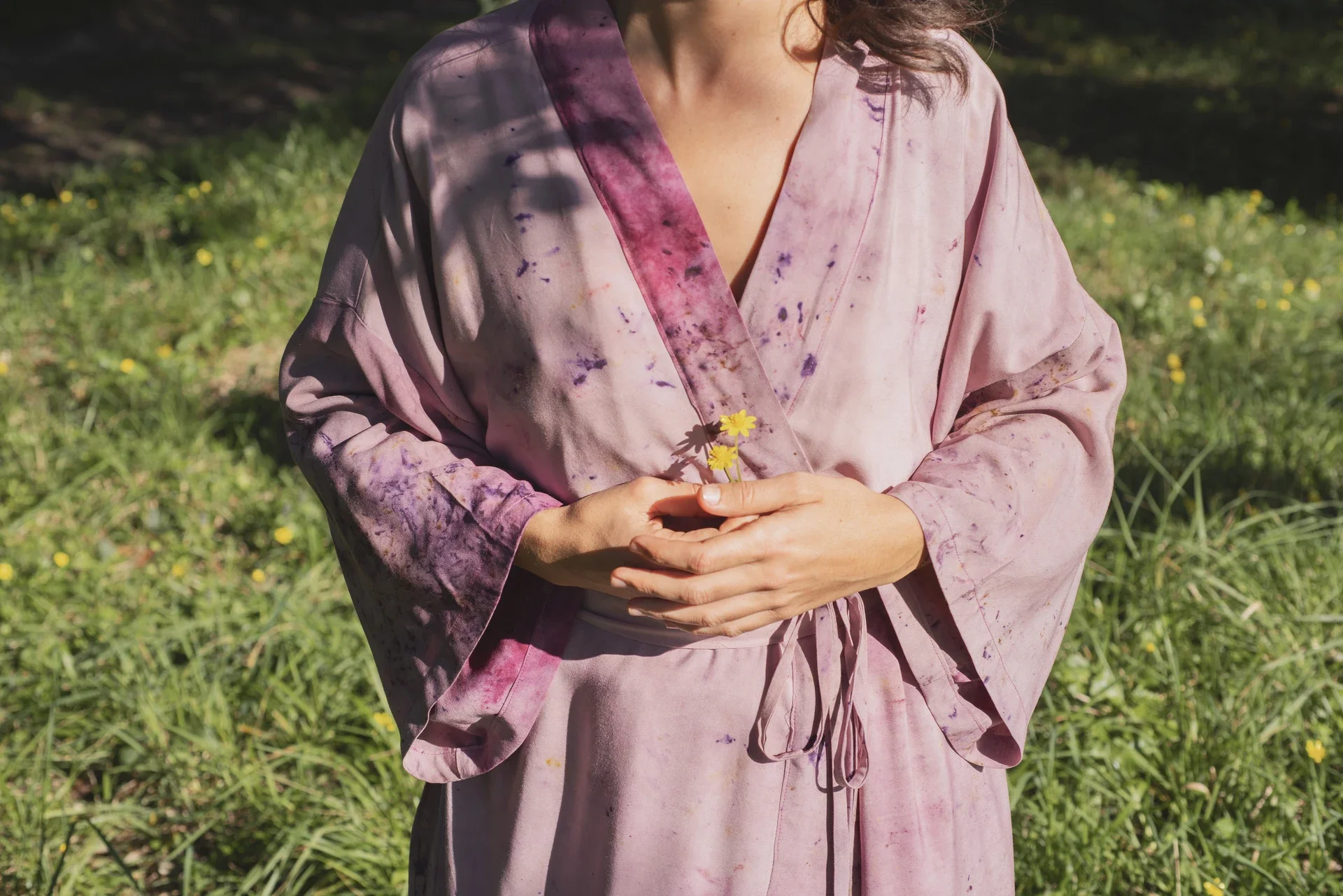 Mujer meditando al aire libre, vistiendo un kimono fluido color morado de fibra de loto con estampado botánico eco-print.