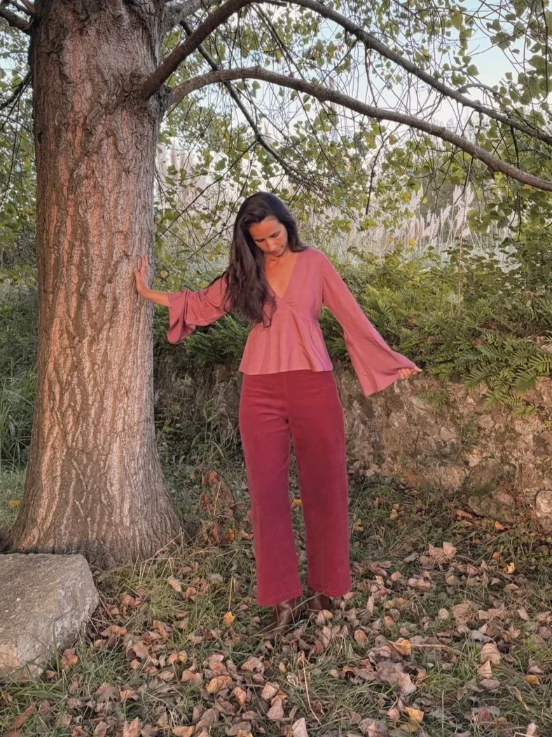 Mujer sonriente en el bosque luciendo el pantalón Indira de pana.