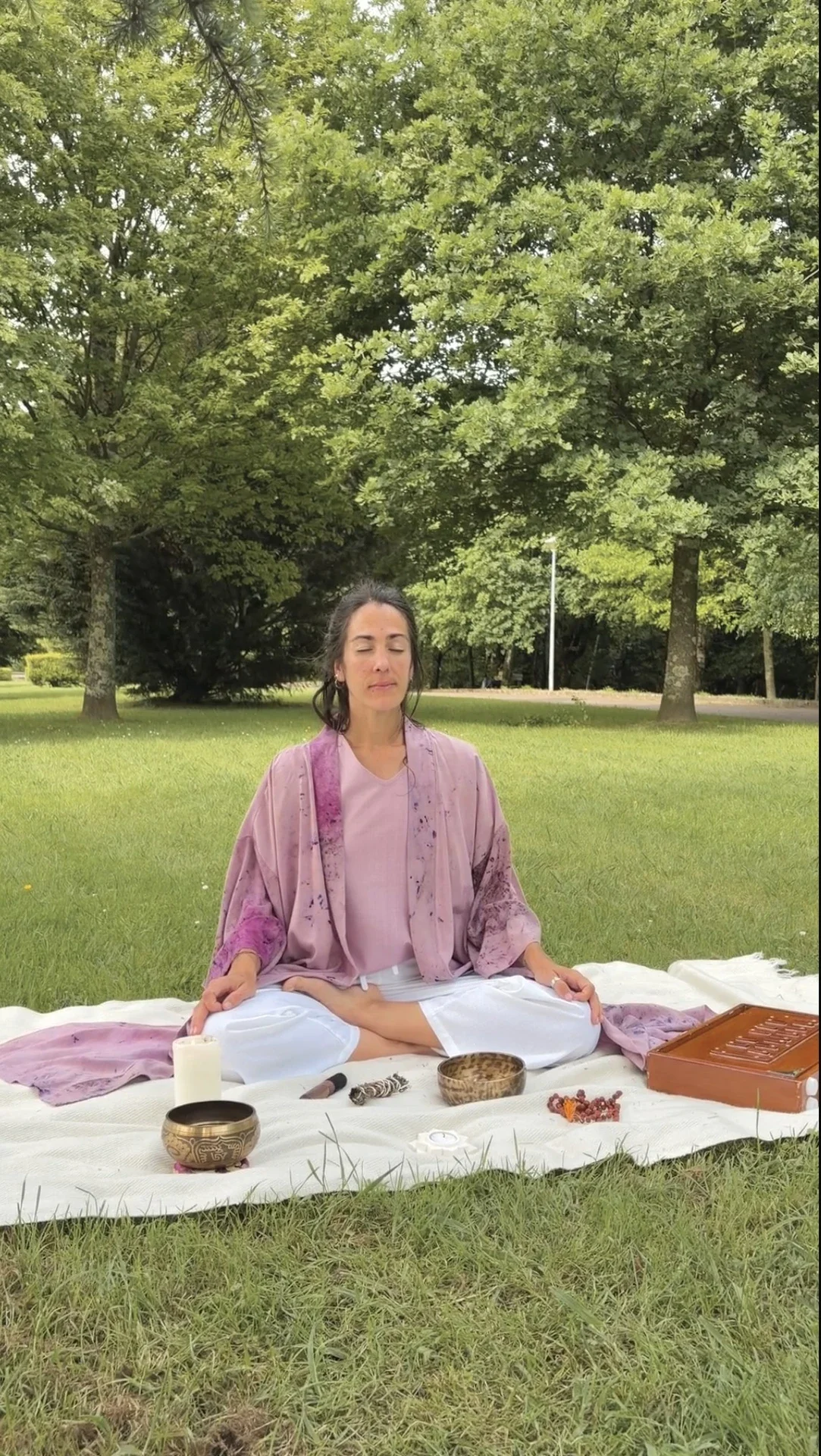 Mujer meditando al aire libre, vistiendo un kimono fluido color morado de fibra de loto con estampado botánico eco-print.