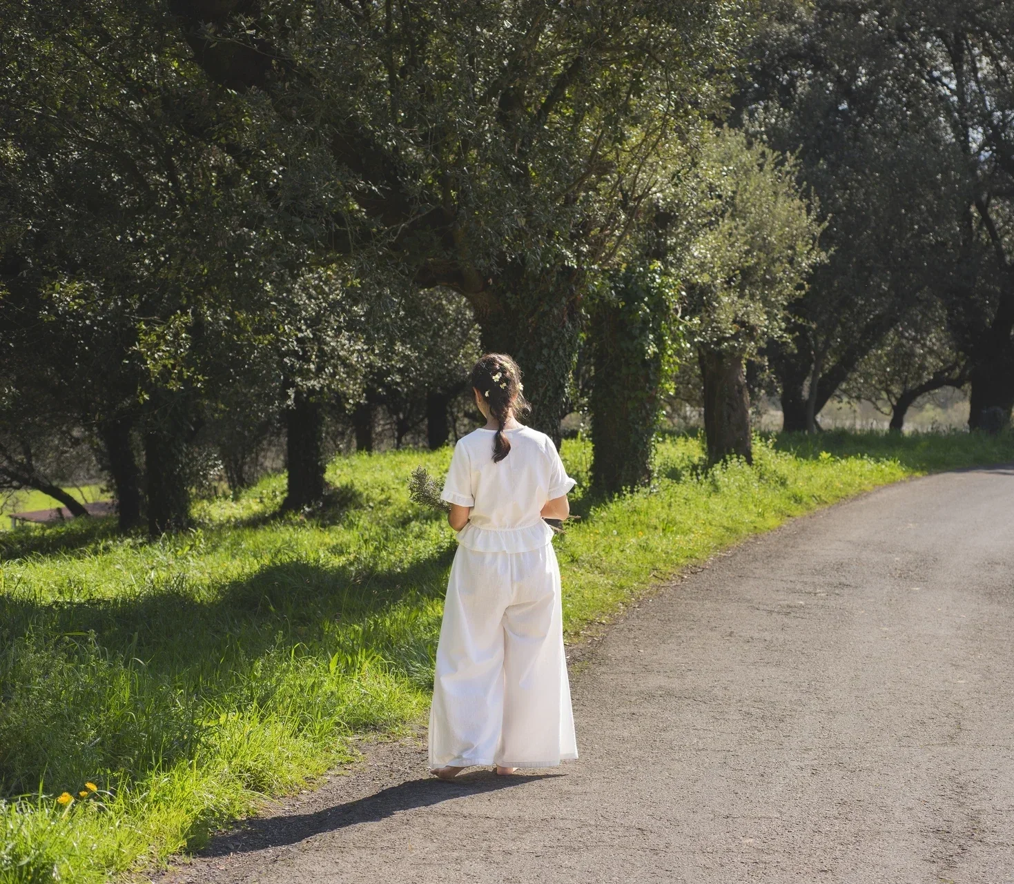 Mujer en la naturaleza vistiendo el Pantalón Orekan de pata ancha en color blanco, confeccionado en algodón orgánico y tintes naturales libres de tóxicos
