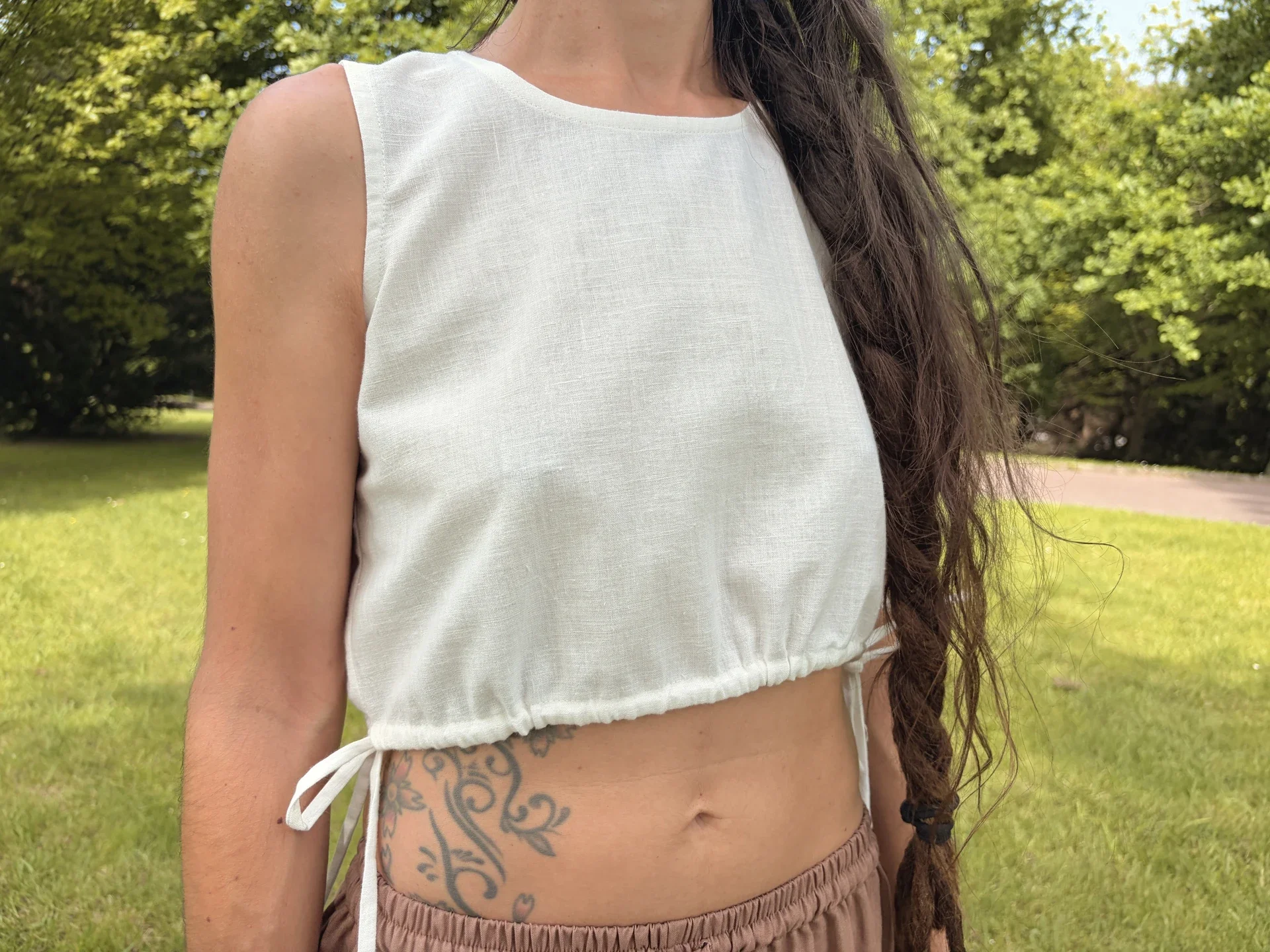Mujer practicando yoga en la naturaleza con un top crop marrón de algodón orgánico teñido con tintes naturales y hierbas medicinales ayurvastra