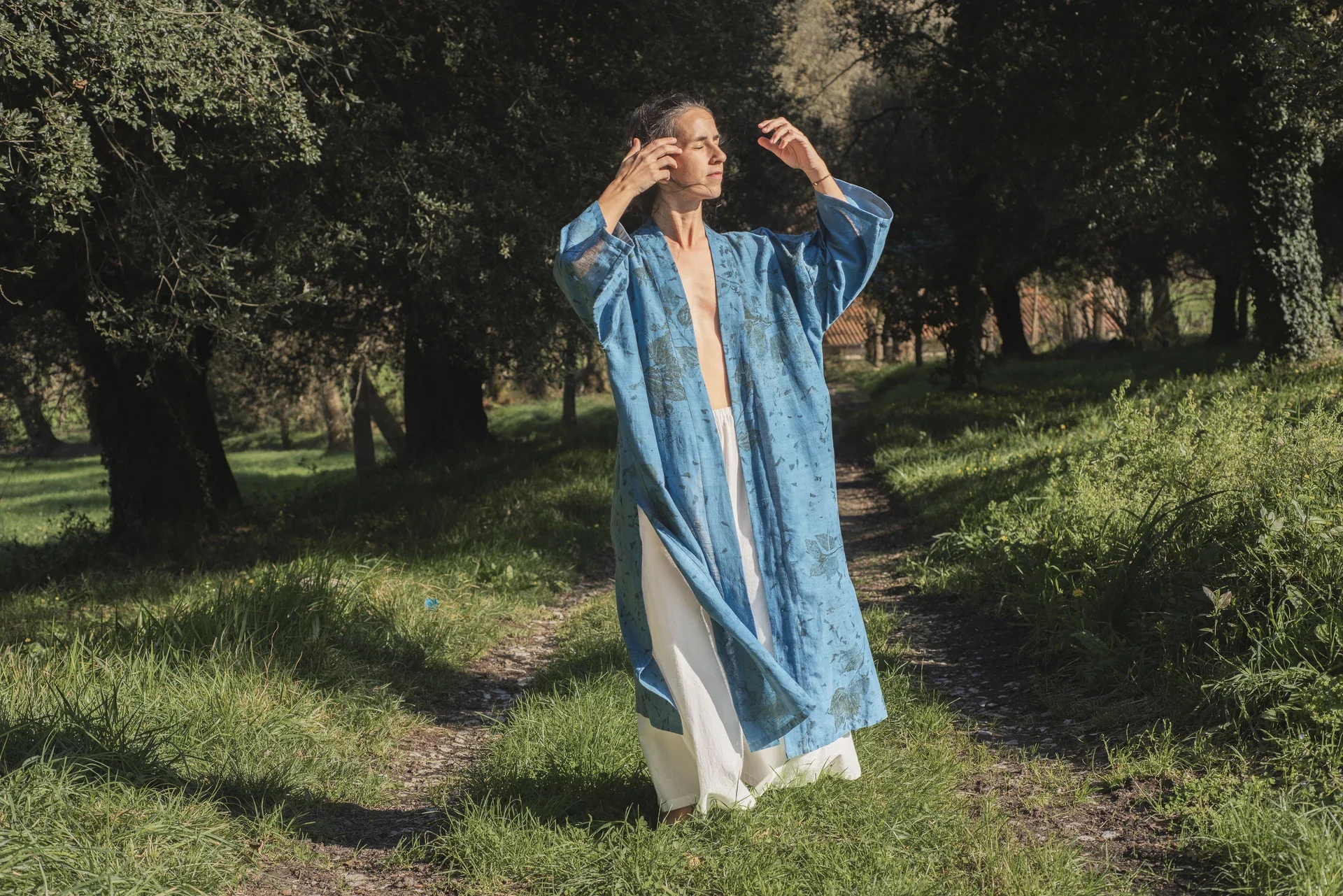 Mujer llevando un kimono azul teñido con índigo natural y estampación botánica en la naturaleza.