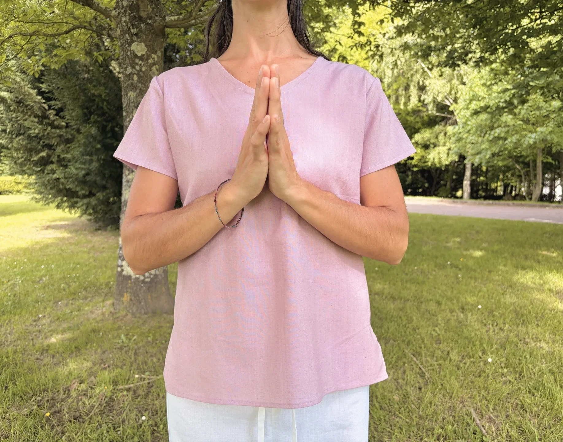 Mujer practicando yoga al aire libre vistiendo un top lila claro de manga corta en algodón orgánico teñido con tintes naturales libre de tóxicos