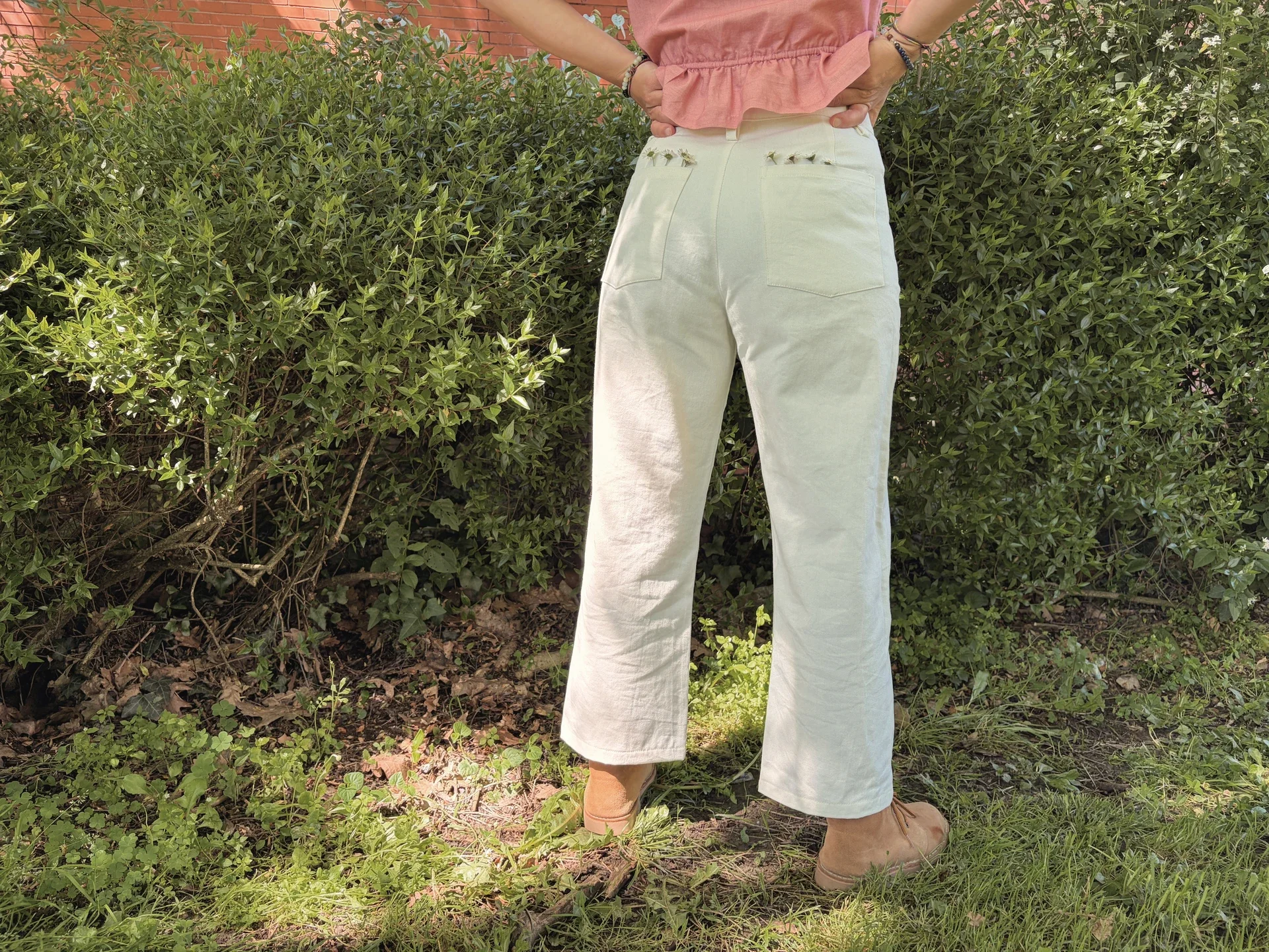 Mujer en la naturaleza vistiendo el Pantalón Luna de estilo denim. Pantalón de corte recto confeccionado en algodón orgánico natural con cierre de botones de coco. Moda consciente y sostenible.