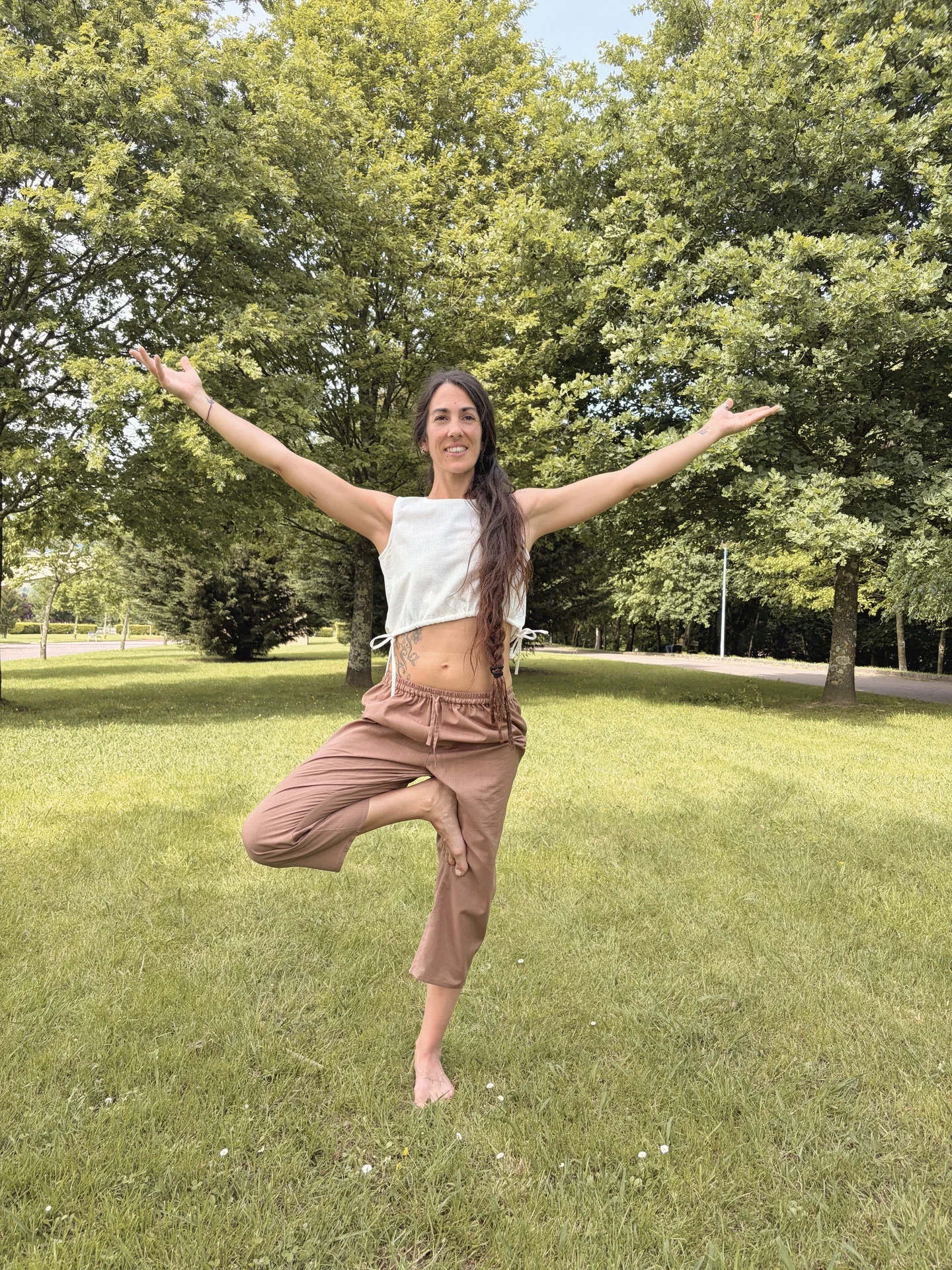 Mujer practicando yoga en la naturaleza con un top crop marrón de algodón orgánico teñido con tintes naturales y hierbas medicinales ayurvastra