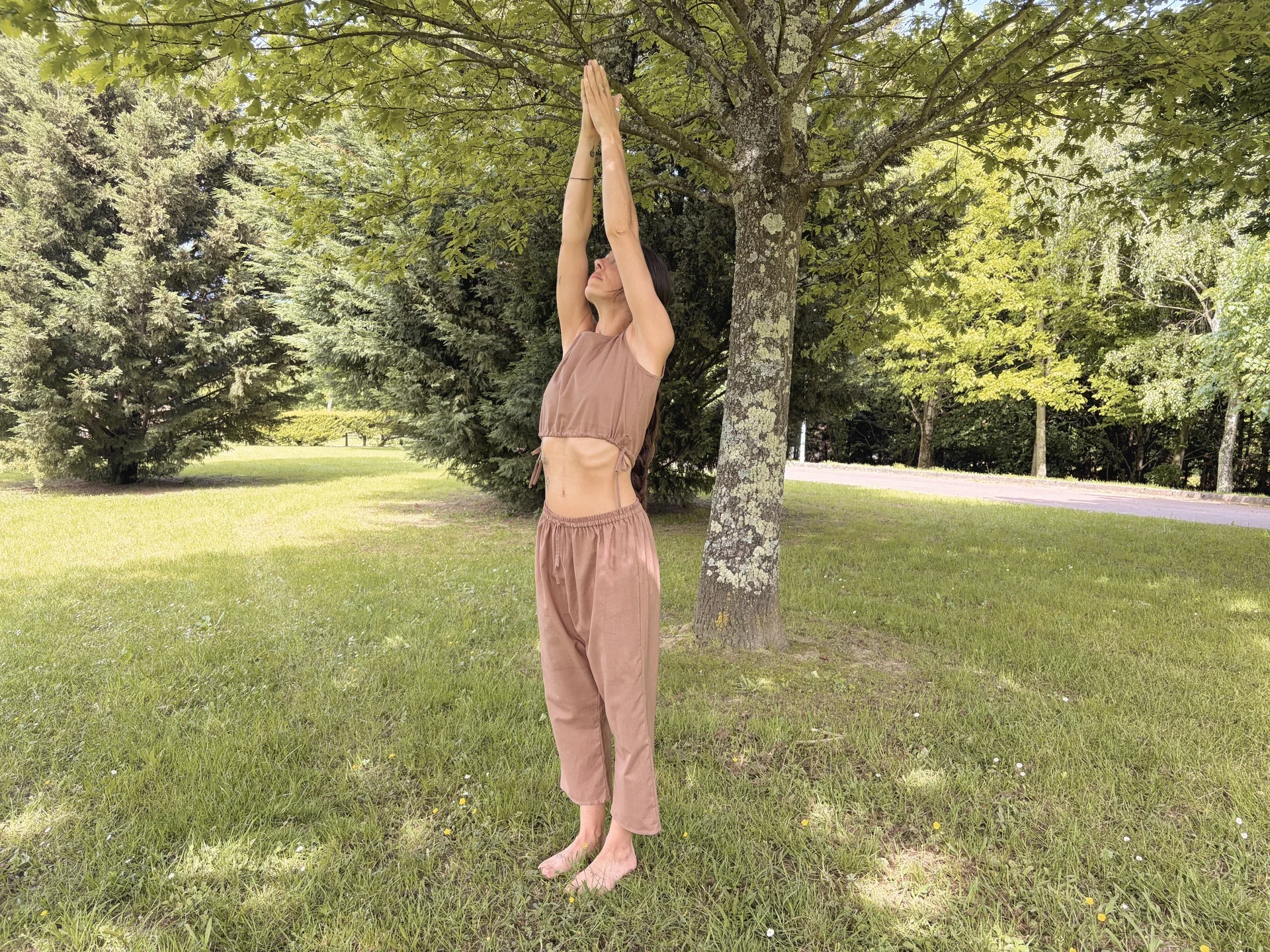 Mujer practicando yoga en la naturaleza con un top crop marrón de algodón orgánico teñido con tintes naturales.