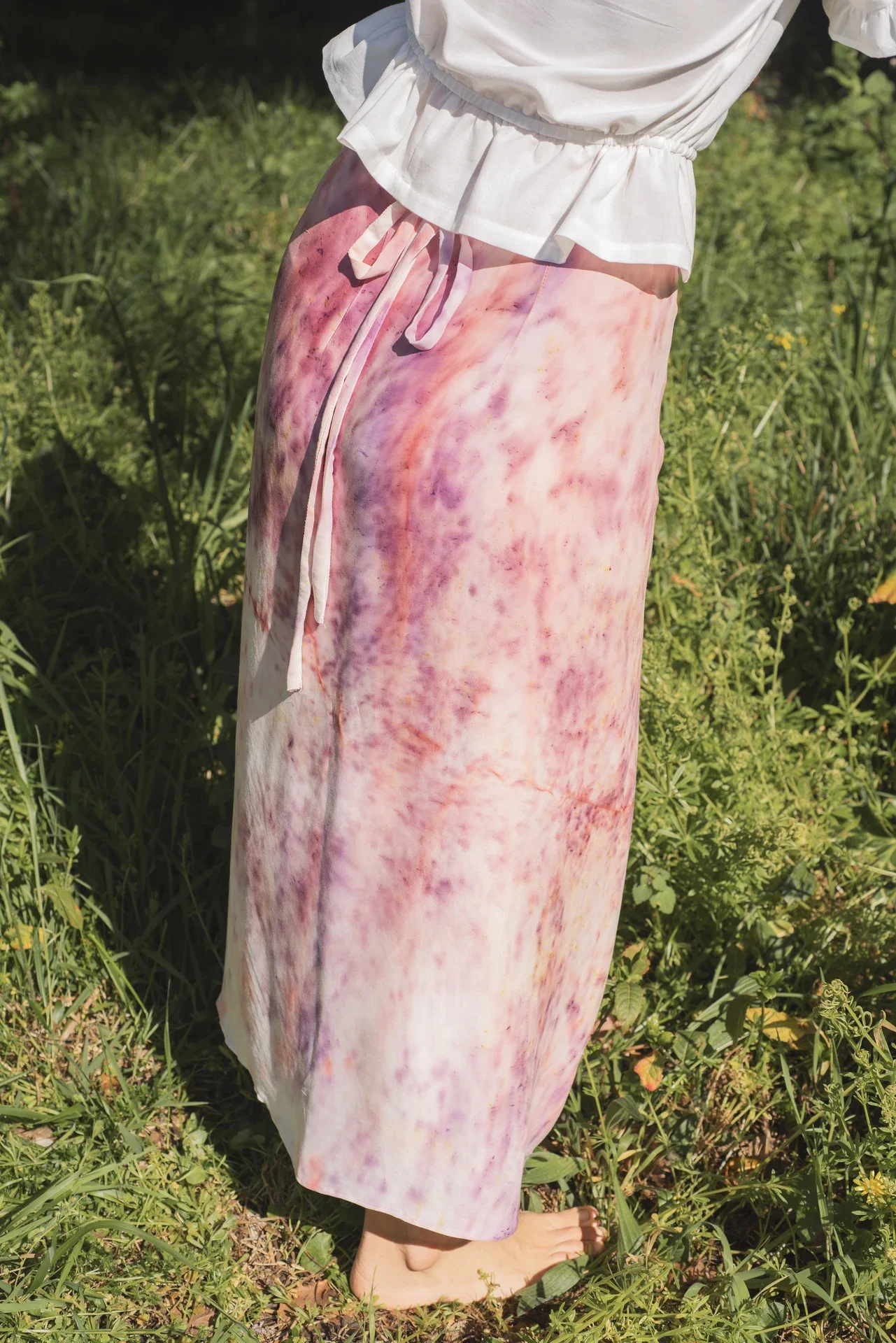 Mujer en la naturaleza vistiendo la falda pareo Prema. Prenda única de diseño artesanal con estampado de flores elaborado a mano en el taller.