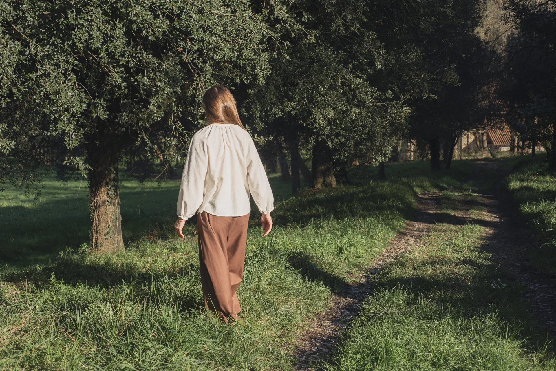Mujer en la naturaleza vistiendo el Pantalón Orekan de pata ancha en color blanco, confeccionado en algodón orgánico y tintes naturales libres de tóxicos