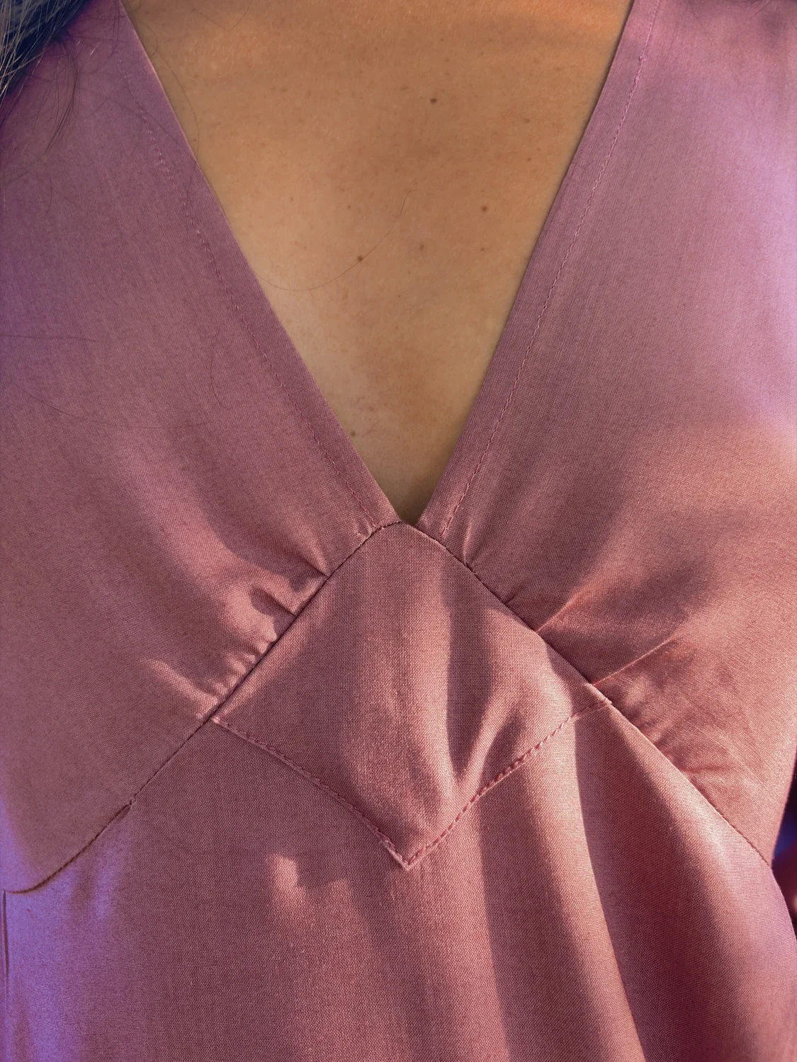 Mujer en la naturaleza luciendo la blusa mística Devi en color violeta, destacando las amplias mangas acampanadas y el tejido teñido con plantas medicinales