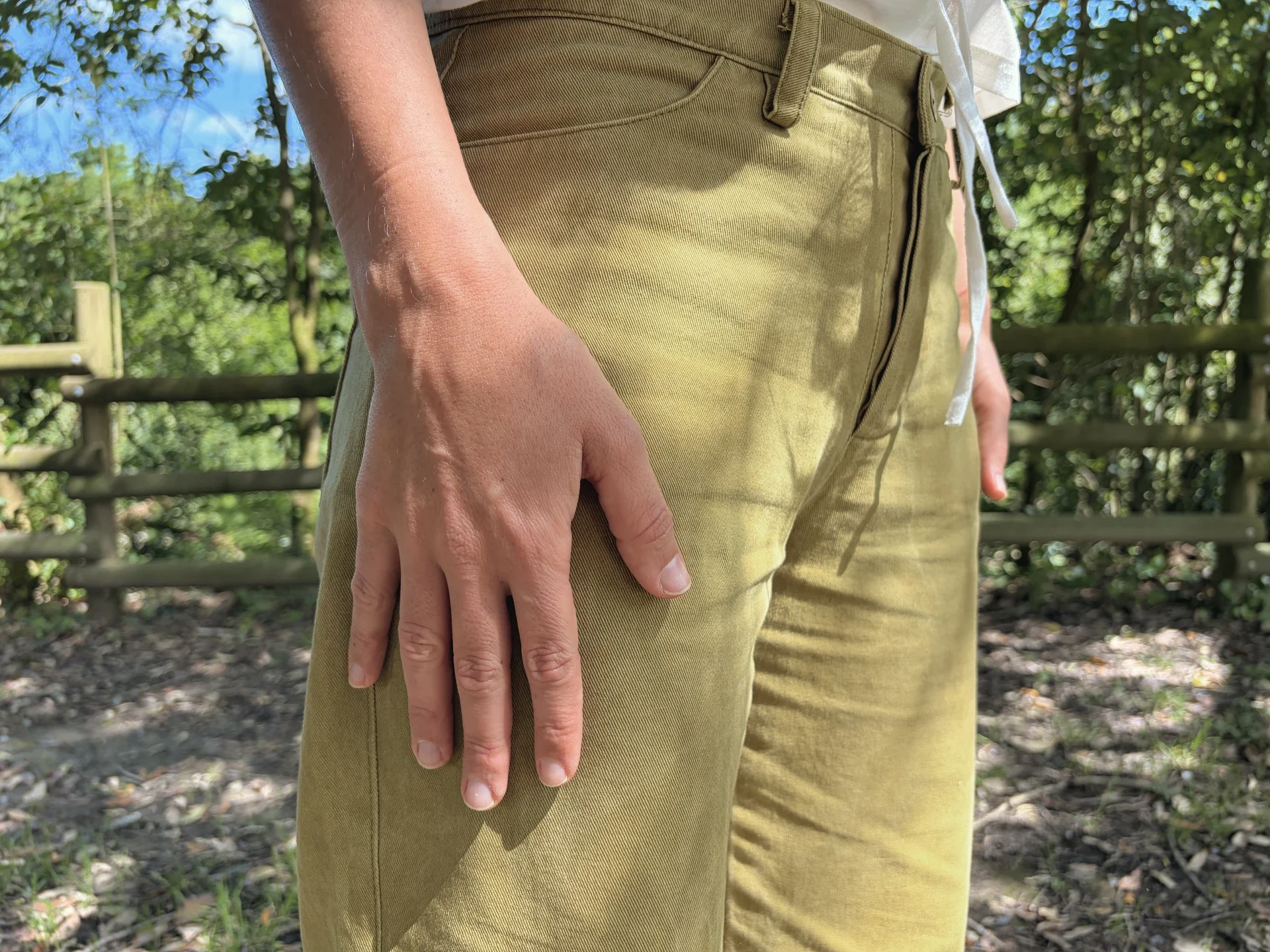 Mujer en la naturaleza vistiendo el Pantalón Luna de estilo denim. Pantalón de corte recto confeccionado en algodón orgánico natural con cierre de botones de coco. Moda consciente y sostenible.