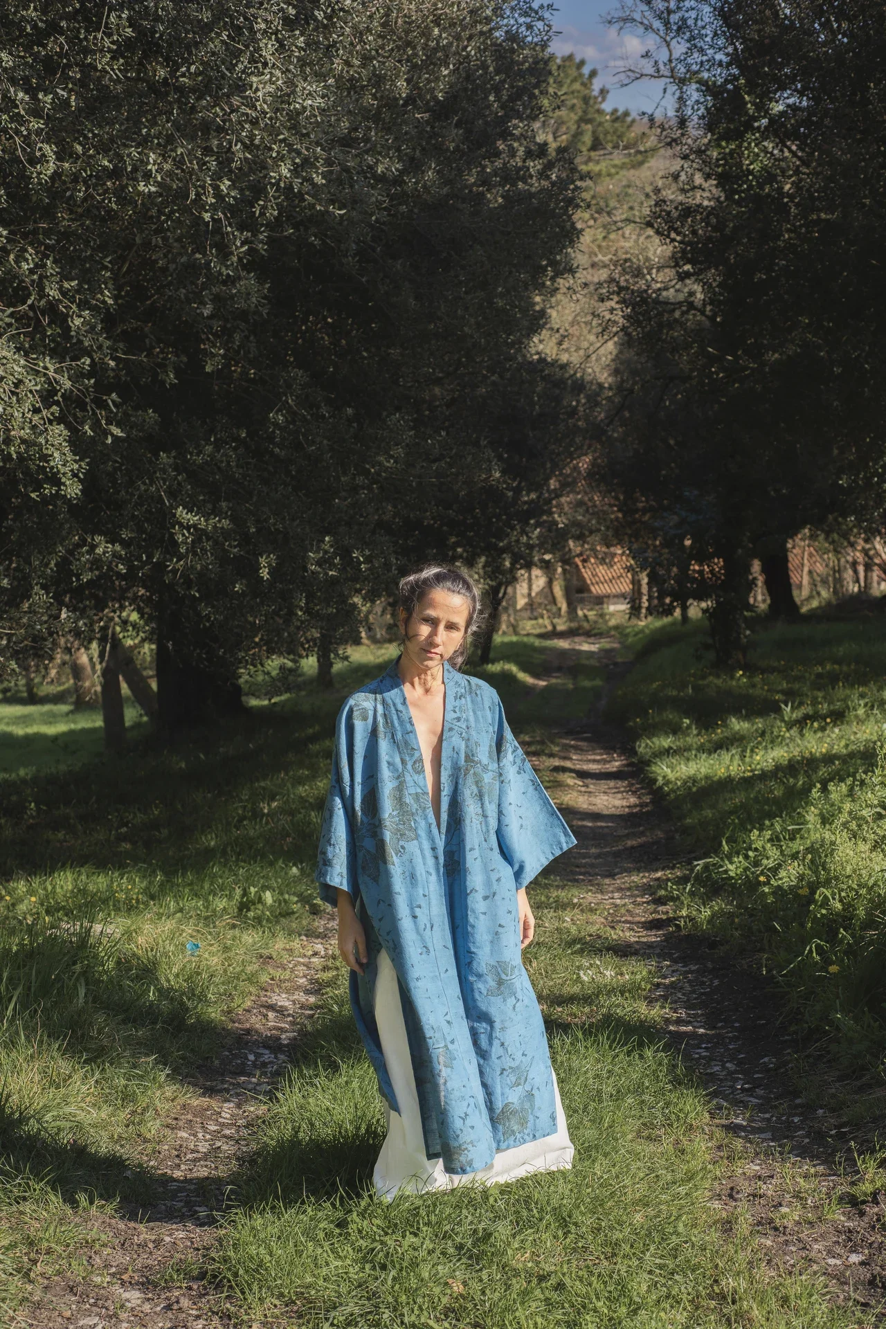 Mujer llevando un kimono azul teñido con índigo natural y estampación botánica en la naturaleza.