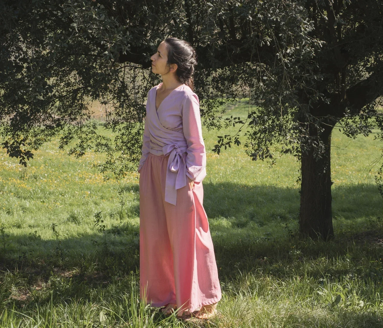 Mujer en la naturaleza vistiendo el Pantalón Orekan de pata ancha en color blanco, confeccionado en algodón orgánico y tintes naturales libres de tóxicos