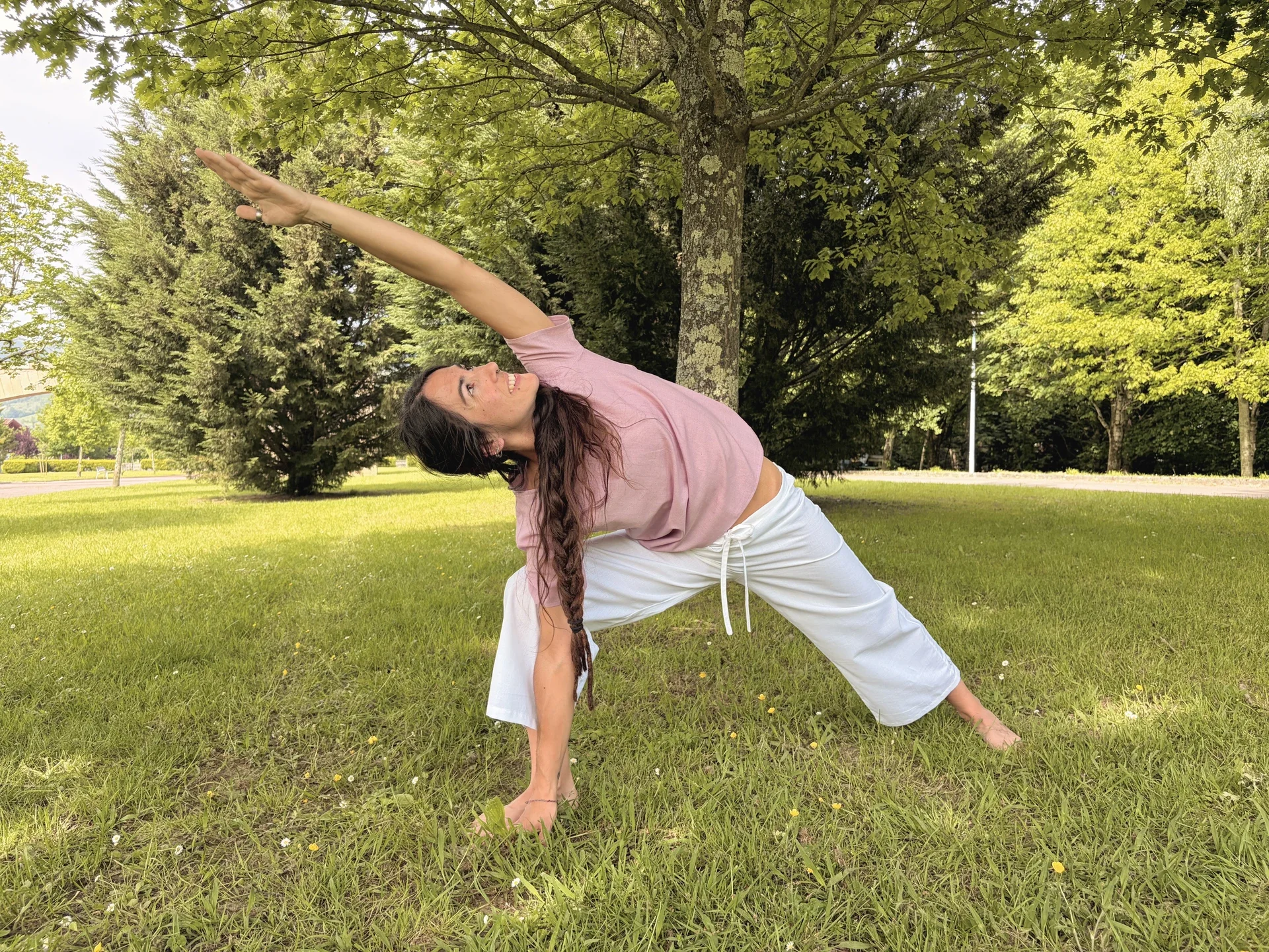 Mujer practicando yoga al aire libre vistiendo un top lila claro de manga corta en algodón orgánico teñido con tintes naturales libre de tóxicos
