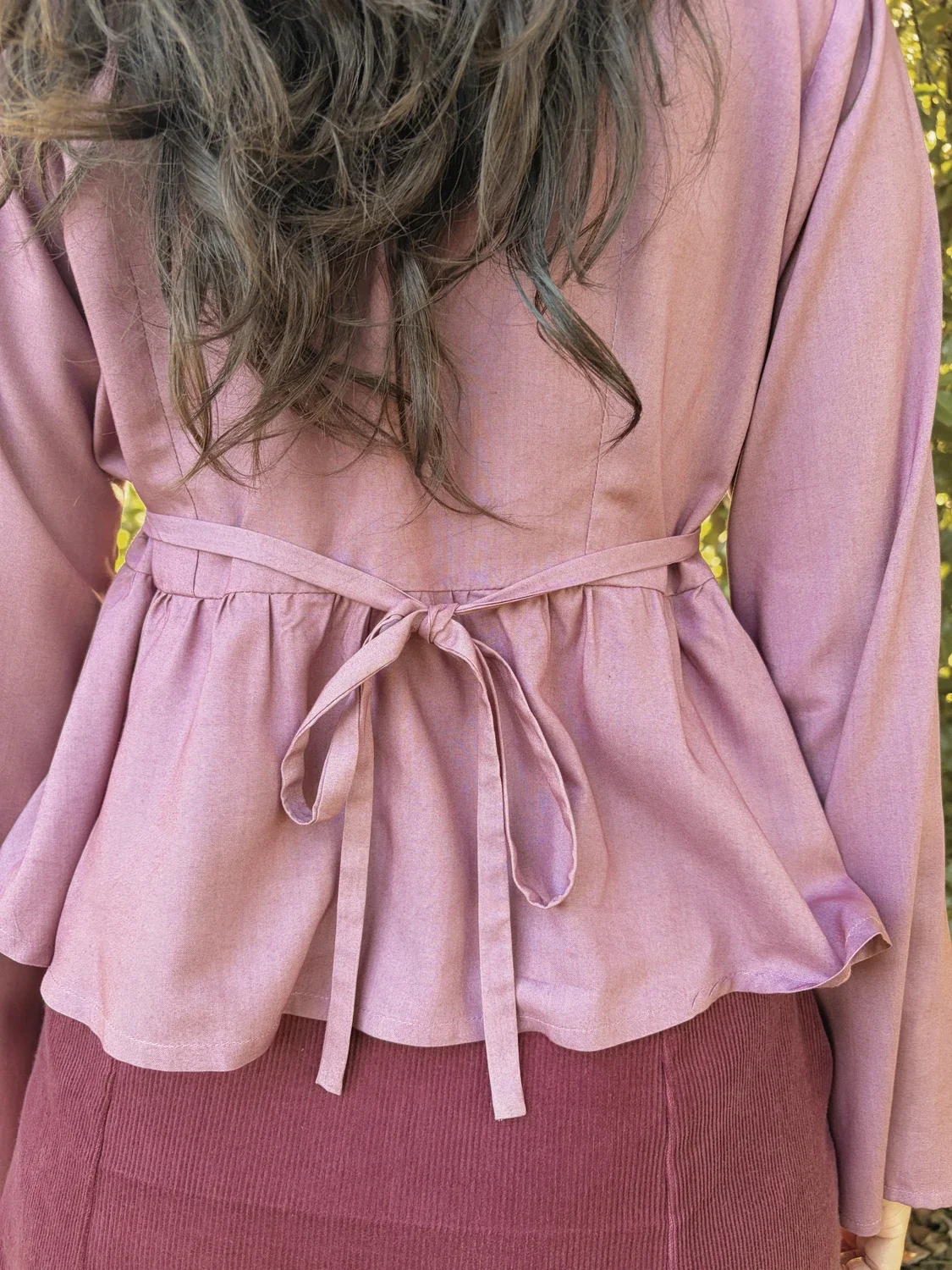 Mujer en la naturaleza luciendo la blusa mística Devi en color violeta, destacando las amplias mangas acampanadas y el tejido teñido con plantas medicinales