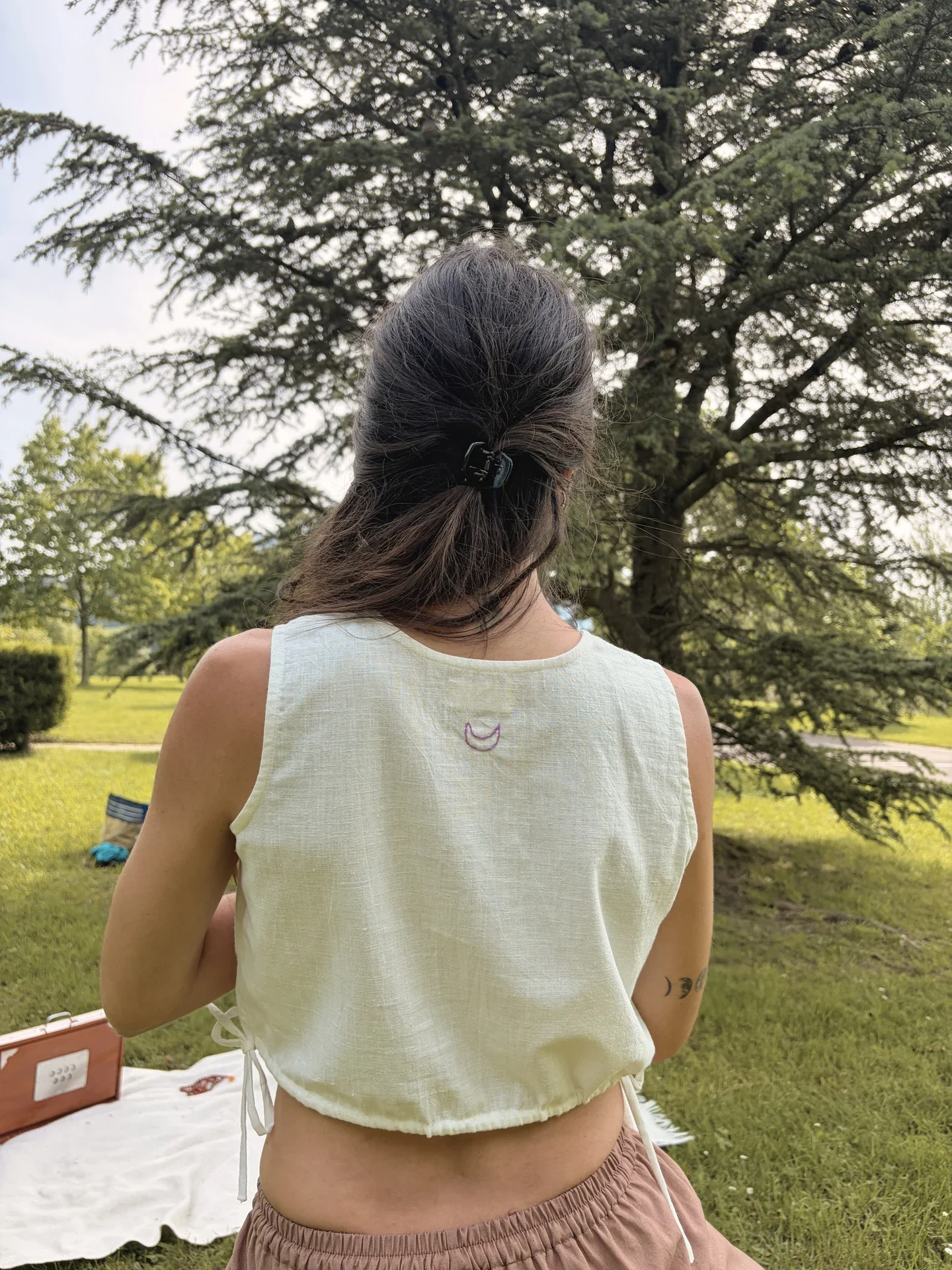 Mujer practicando yoga en la naturaleza con un top crop marrón de algodón orgánico teñido con tintes naturales y hierbas medicinales ayurvastra