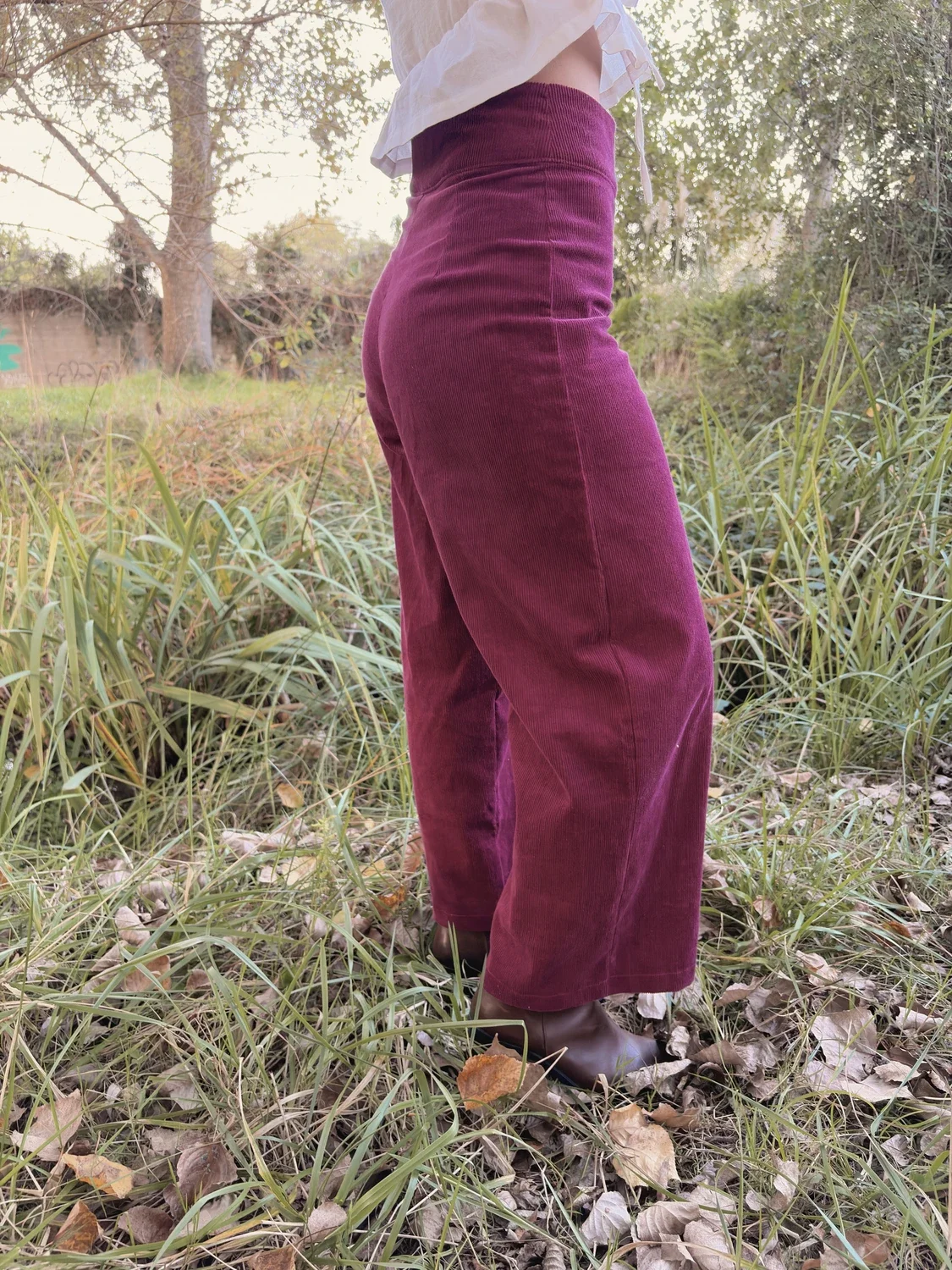 Mujer sonriente en el bosque luciendo el pantalón Indira de pana.