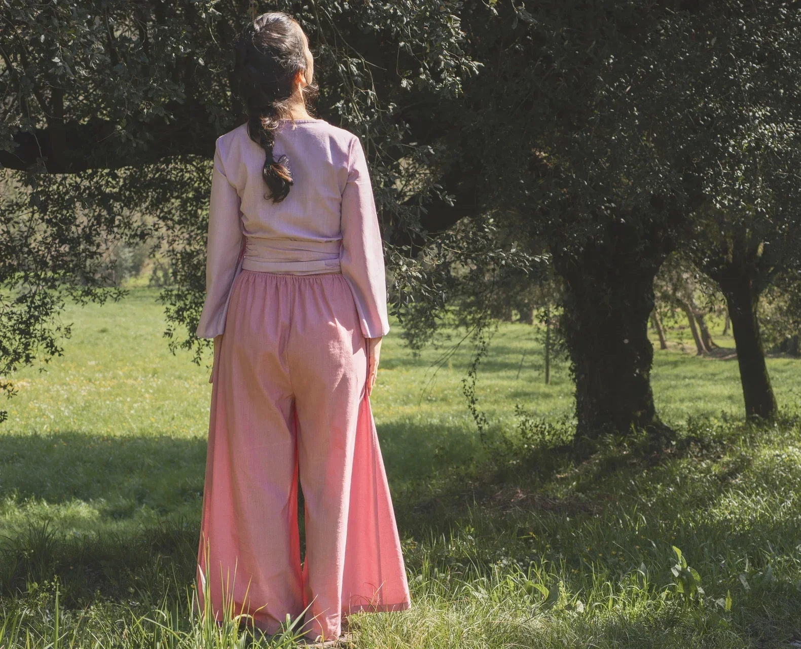 Mujer en la naturaleza vistiendo el Pantalón Orekan de pata ancha en color blanco, confeccionado en algodón orgánico y tintes naturales libres de tóxicos