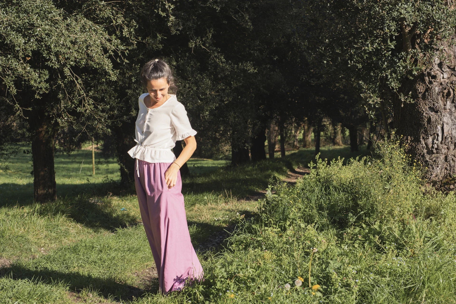 Mujer en la naturaleza vistiendo el Pantalón Orekan de pata ancha en color blanco, confeccionado en algodón orgánico y tintes naturales libres de tóxicos