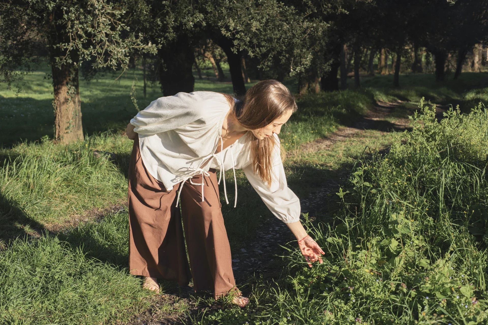 Mujer en la naturaleza vistiendo el Pantalón Orekan de pata ancha en color blanco, confeccionado en algodón orgánico y tintes naturales libres de tóxicos