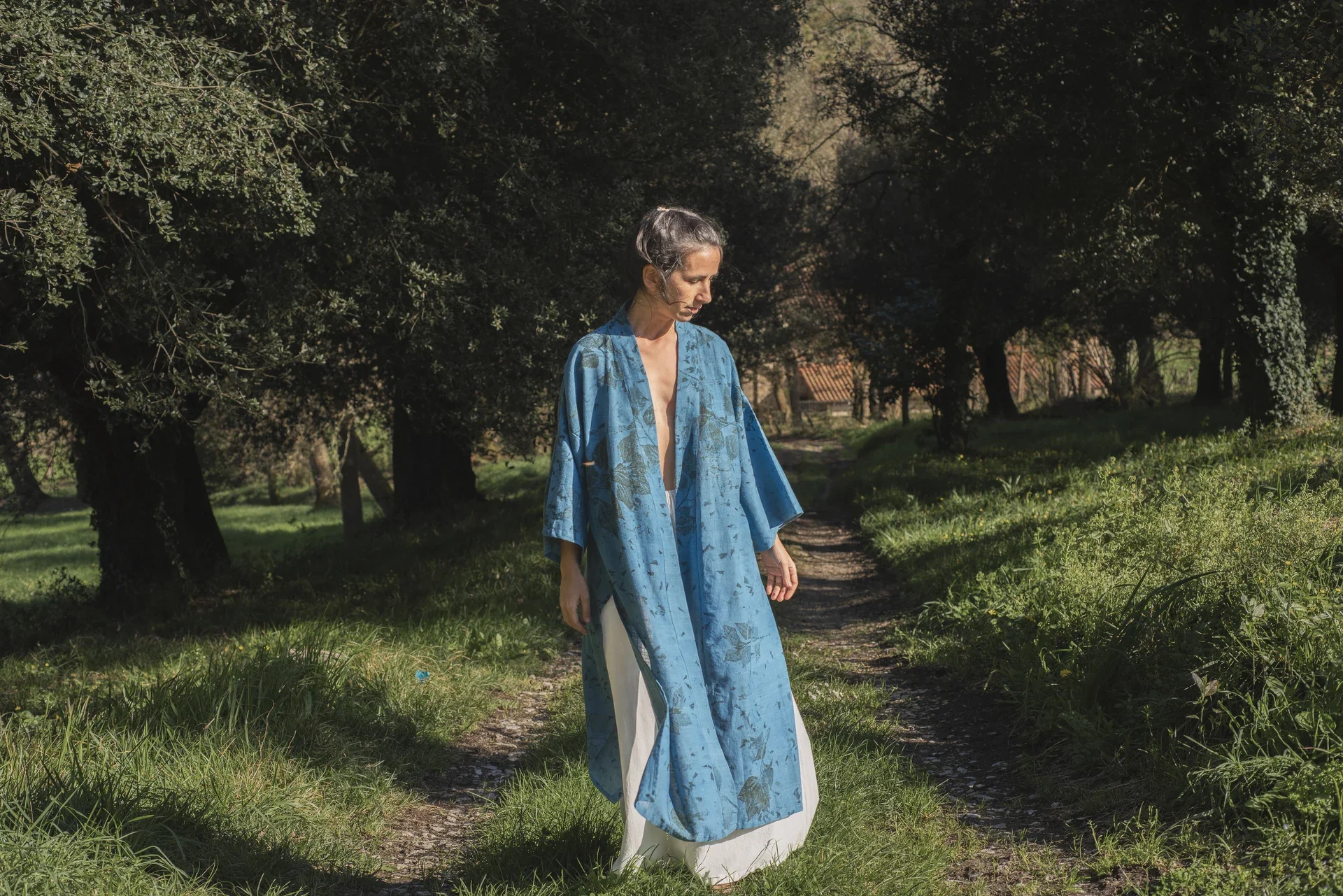 Mujer llevando un kimono azul teñido con índigo natural y estampación botánica en la naturaleza.