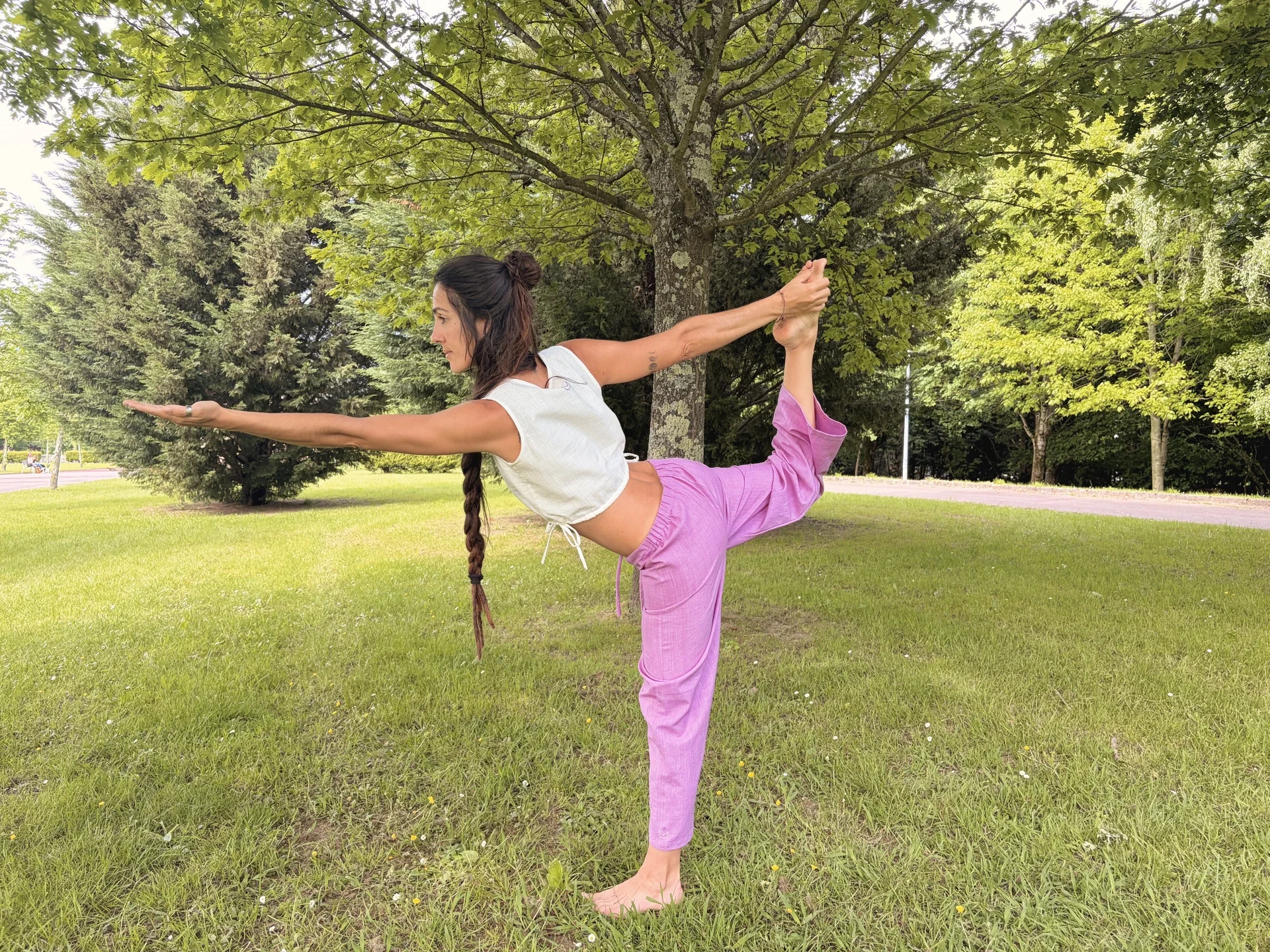 Mujer practicando yoga en la naturaleza con un top crop marrón de algodón orgánico teñido con tintes naturales.