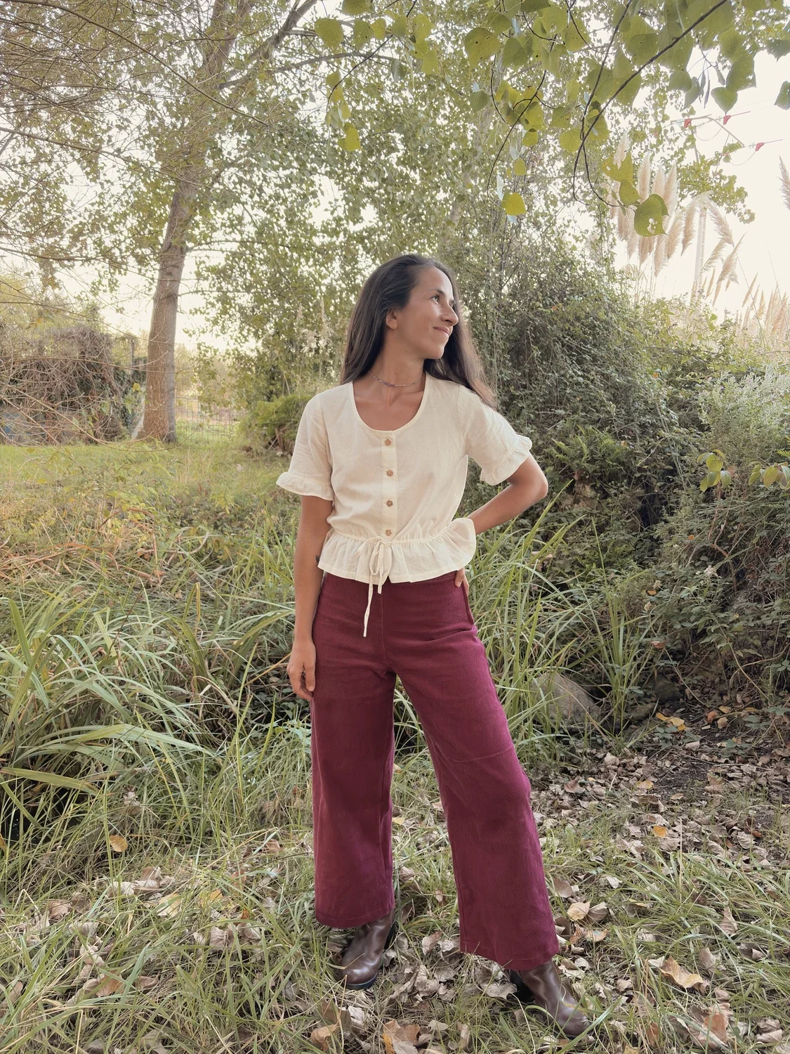 Mujer sonriente en el bosque luciendo el pantalón Indira de pana.
